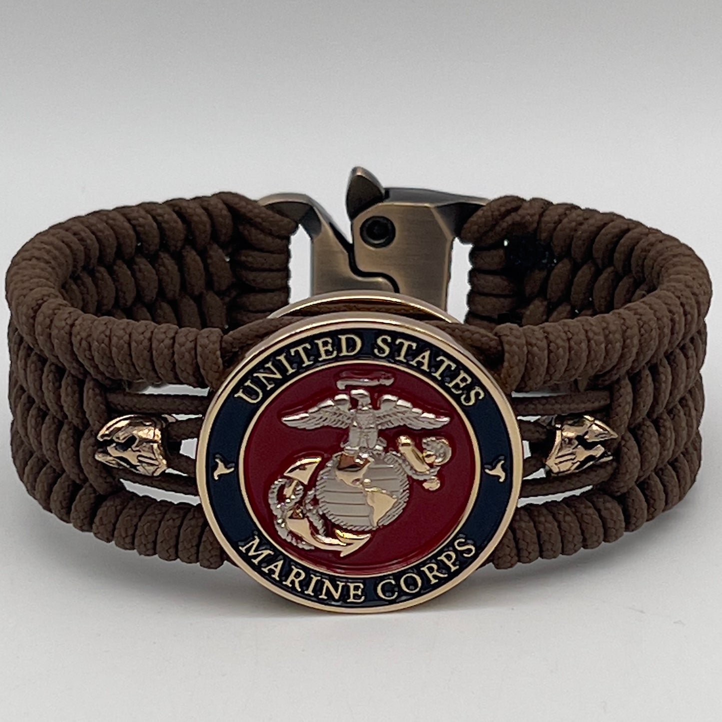 Thin, medium width, flexible and comfortable braided United States Marine Corps bracelet featuring a 24K gold and silver plated USMC officer Eagle Globe and Anchor medallion, two brass micro Spartan helmets, a gold Cobra style tactical buckle and woven with Coyote Brown type-1 paracord.