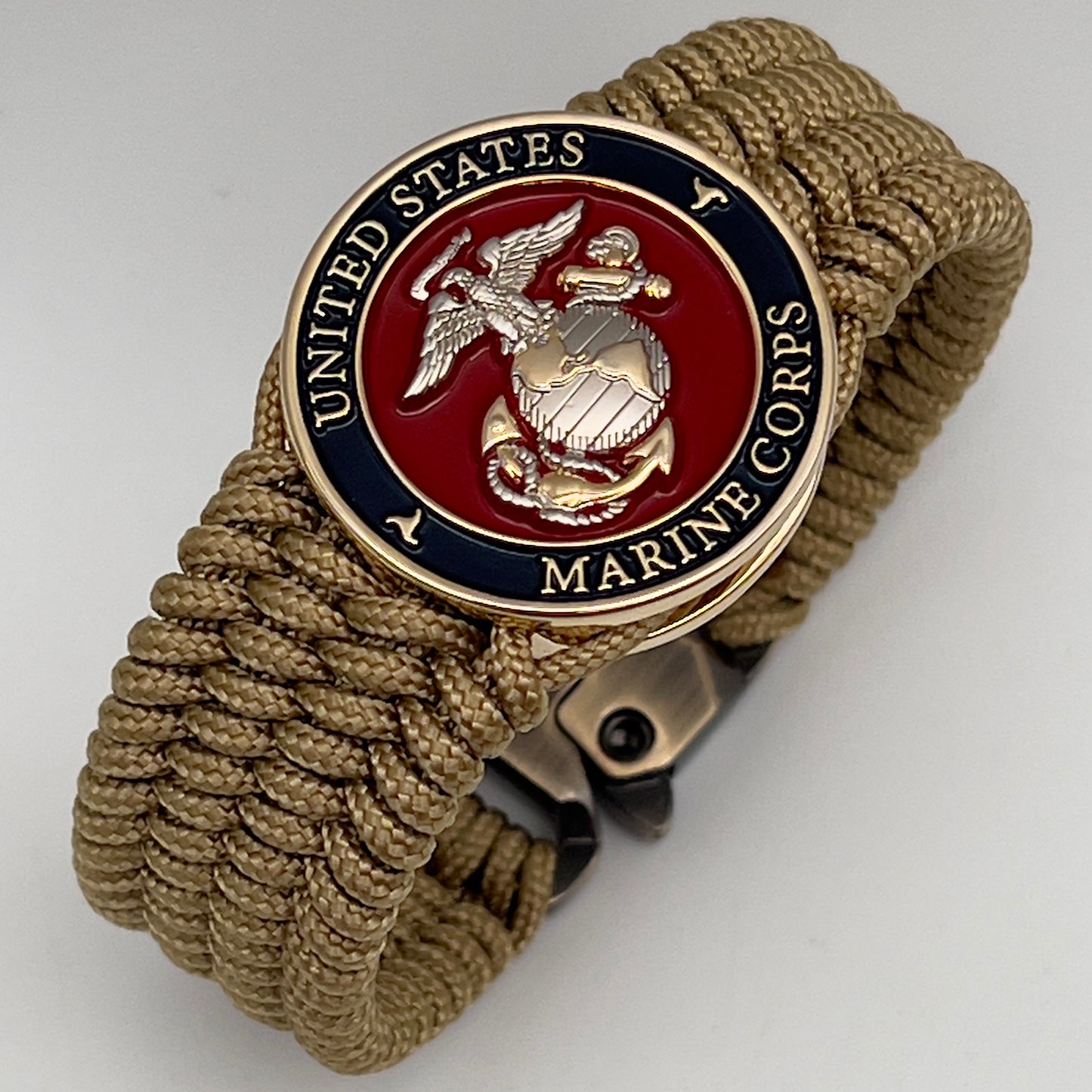Thin, wide, flexible and comfortable braided United States Marine Corps bracelet featuring a 24K gold and silver plated USMC Eagle Globe and Anchor medallion, a gold Cobra style tactical buckle and woven with gold type-1 paracord.
