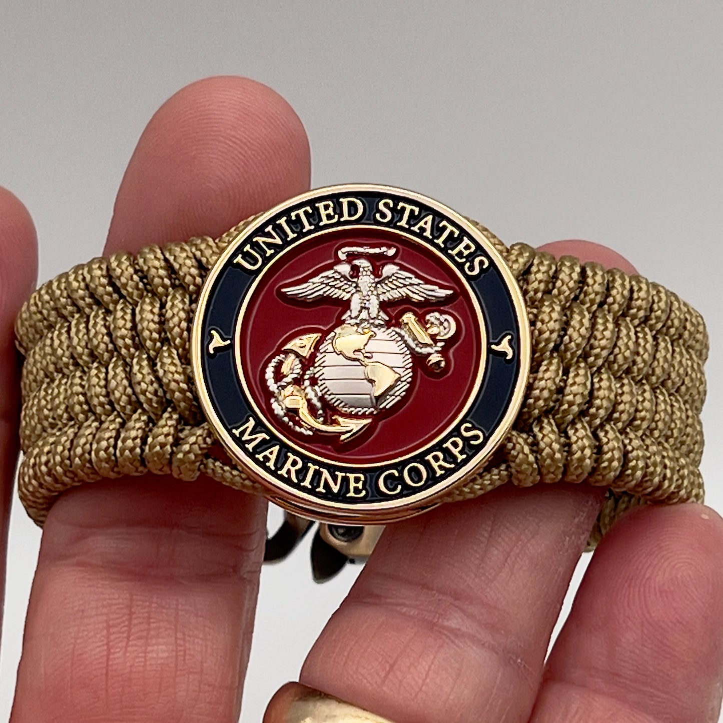 Thin, wide, flexible and comfortable braided United States Marine Corps bracelet featuring a 24K gold and silver plated USMC Eagle Globe and Anchor medallion, a gold Cobra style tactical buckle and woven with gold type-1 paracord.