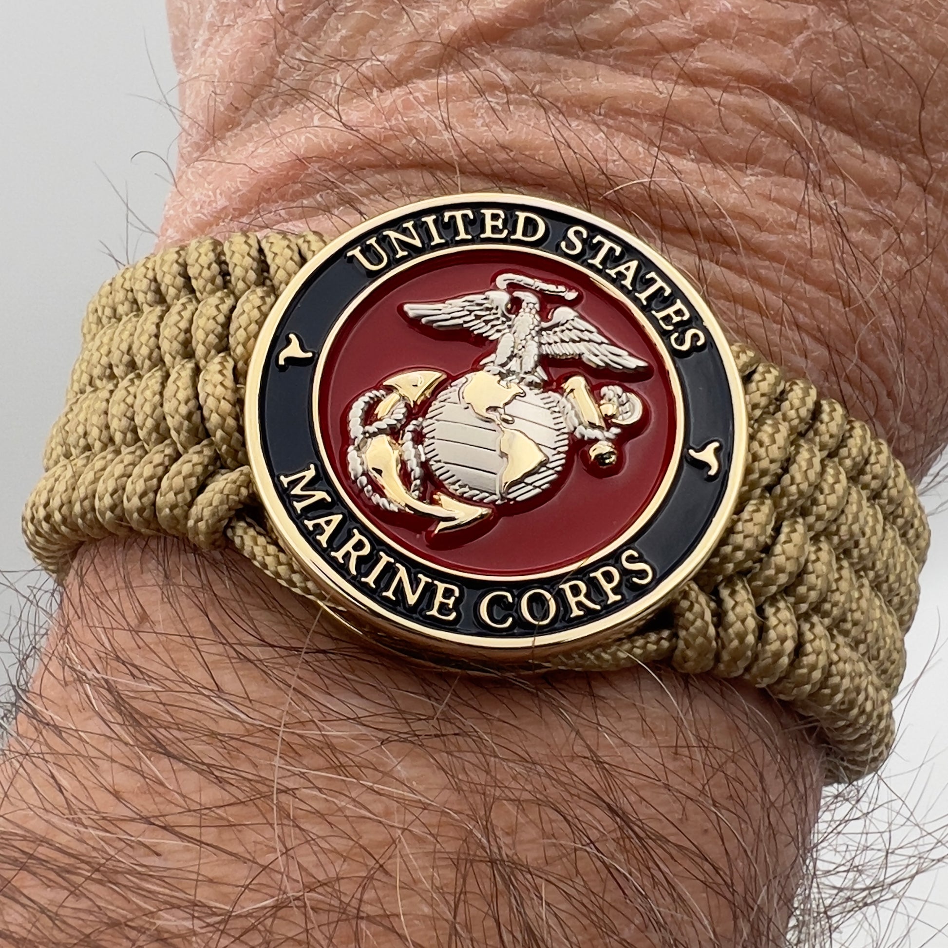 Thin, wide, flexible and comfortable braided United States Marine Corps bracelet featuring a 24K gold and silver plated USMC Eagle Globe and Anchor medallion, a gold Cobra style tactical buckle and woven with gold type-1 paracord.