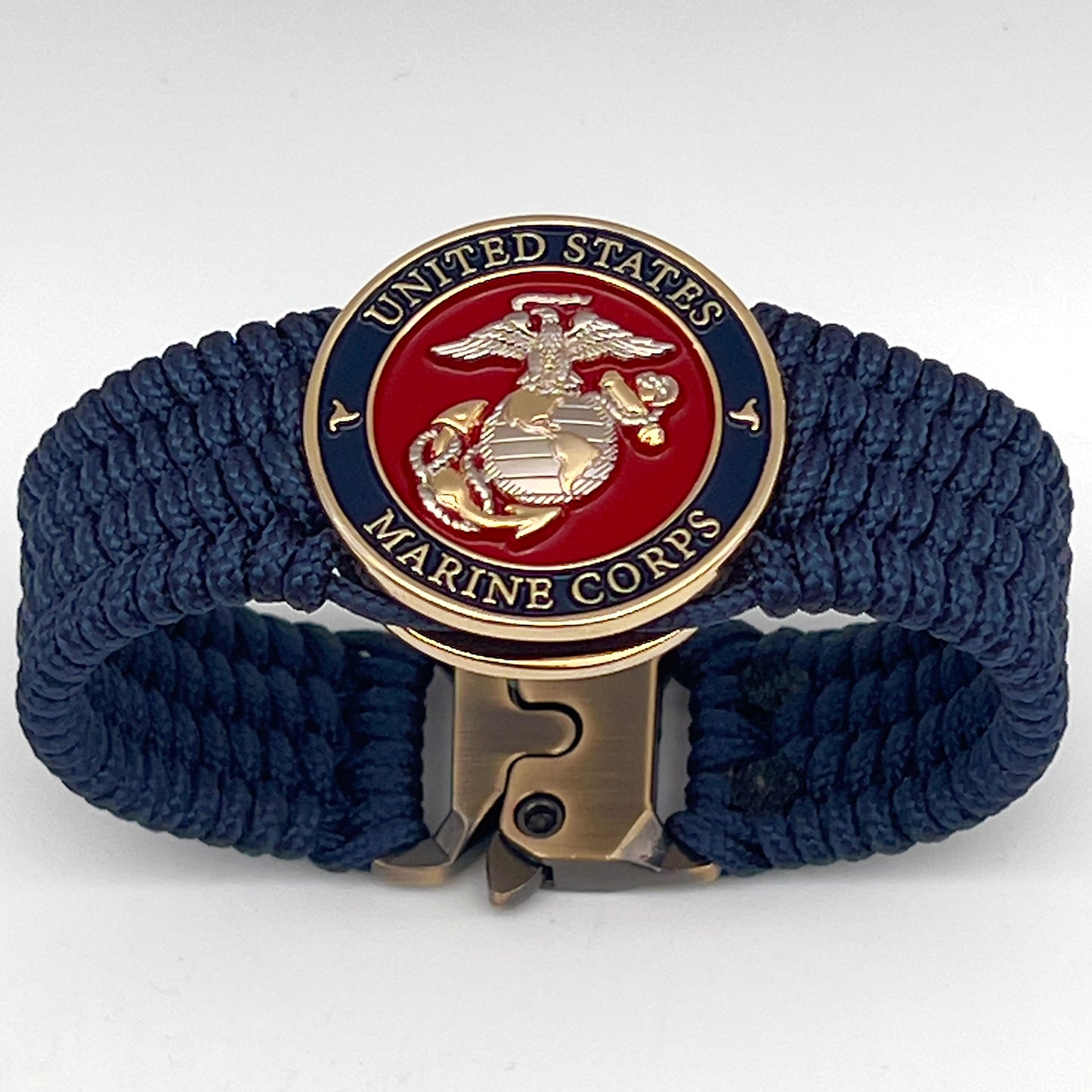 Thin, wide, flexible and comfortable braided United States Marine Corps bracelet featuring a 24K gold and silver plated USMC Eagle Globe and Anchor medallion, a gold Cobra style tactical buckle and woven with Navy blue type-1 paracord.