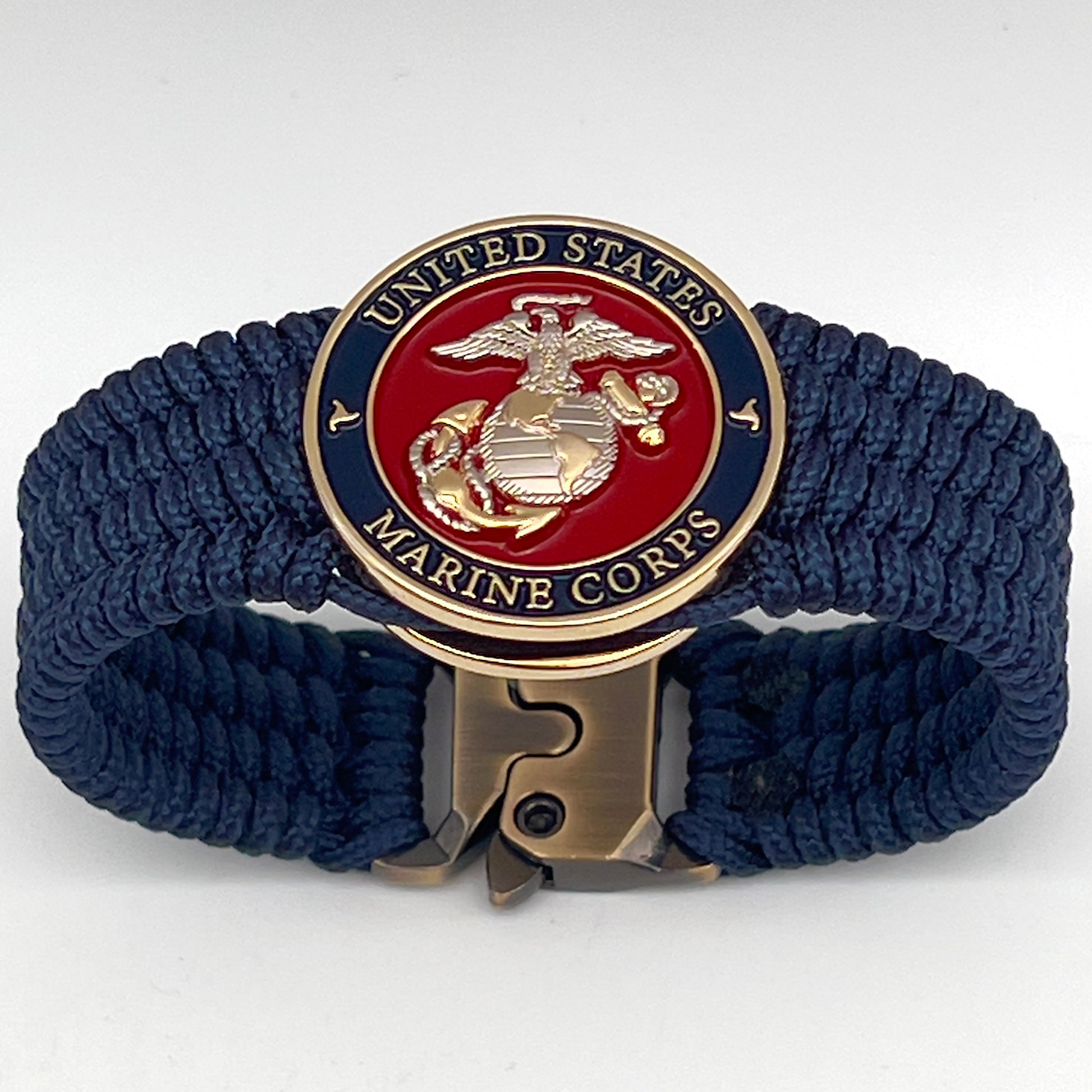 Thin, wide, flexible and comfortable braided United States Marine Corps bracelet featuring a 24K gold and silver plated USMC Eagle Globe and Anchor medallion, a gold Cobra style tactical buckle and woven with Navy blue type-1 paracord.