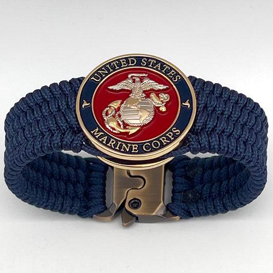 Thin, wide, flexible and comfortable braided United States Marine Corps bracelet featuring a 24K gold and silver plated USMC Eagle Globe and Anchor medallion, a gold Cobra style tactical buckle and woven with Navy blue type-1 paracord.