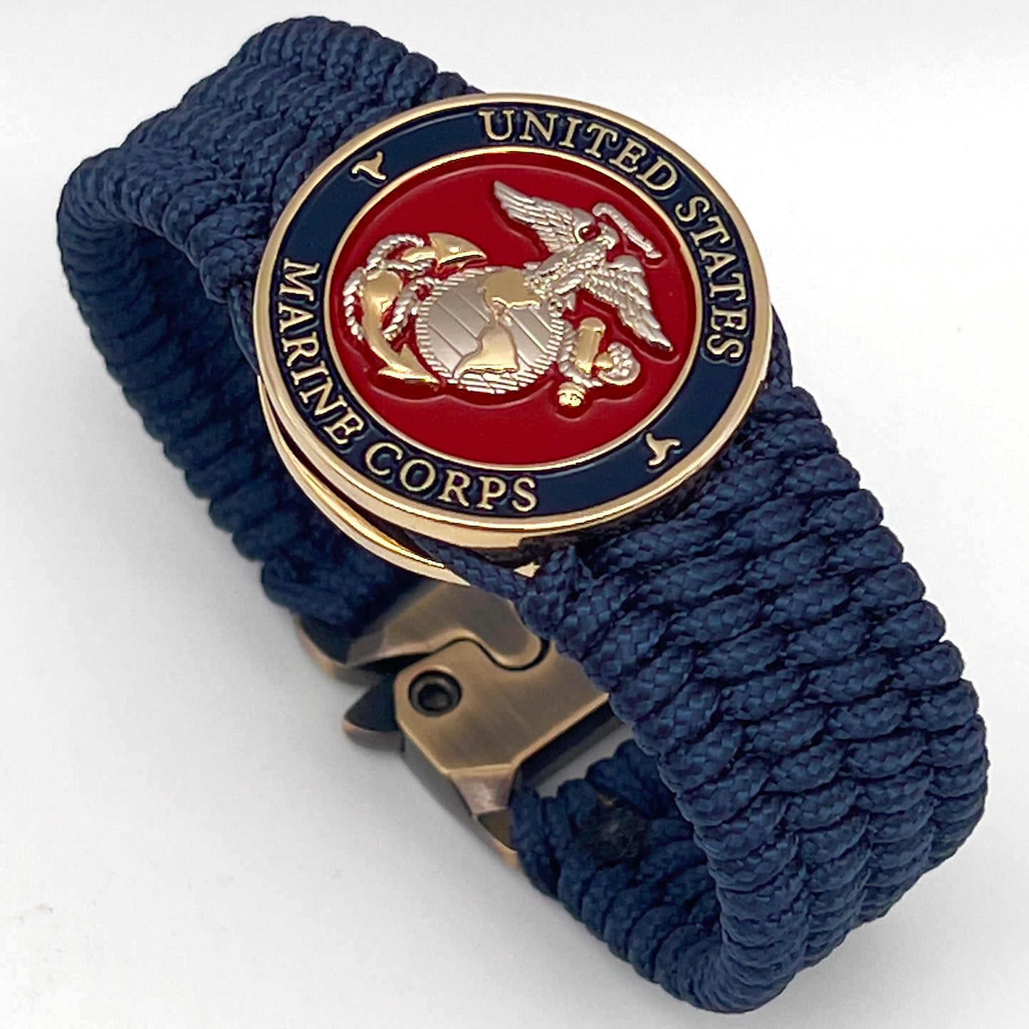 Thin, wide, flexible and comfortable braided United States Marine Corps bracelet featuring a 24K gold and silver plated USMC Eagle Globe and Anchor medallion, a gold Cobra style tactical buckle and woven with Navy blue type-1 paracord.
