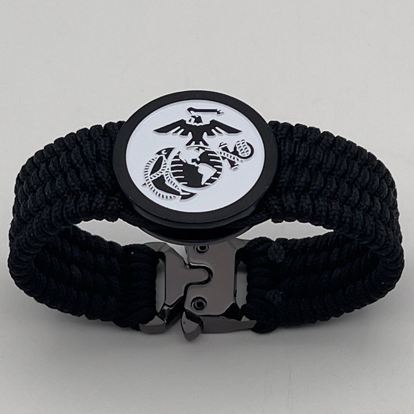 Thin, medium width, flexible and comfortable braided United States Marine Corps bracelet featuring a black USMC Eagle Globe and Anchor medallion, a black Cobra style tactical buckle and woven with black Type-1 paracord.