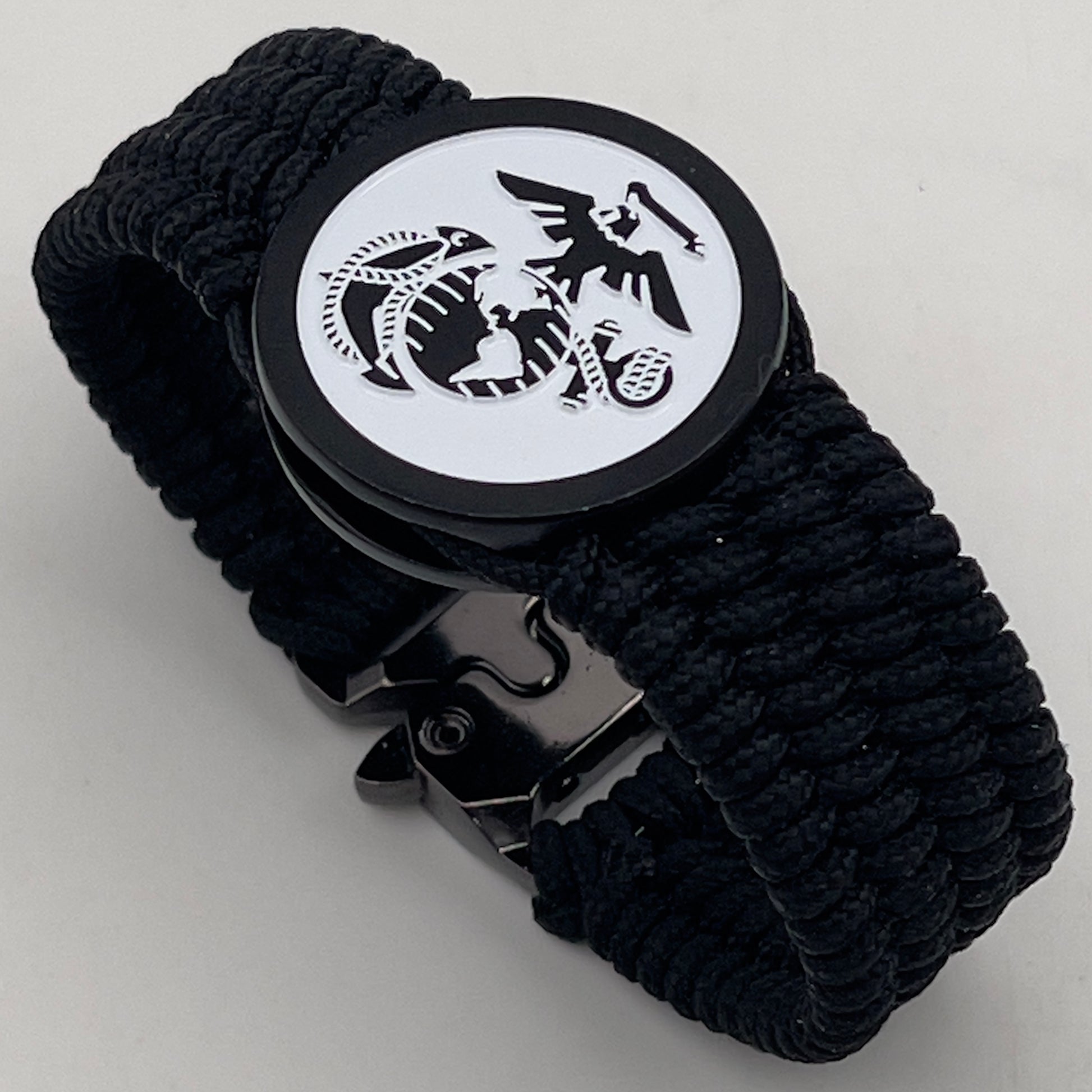 Thin, medium width, flexible and comfortable braided United States Marine Corps bracelet featuring a black USMC Eagle Globe and Anchor medallion, a black Cobra style tactical buckle and woven with black Type-1 paracord.