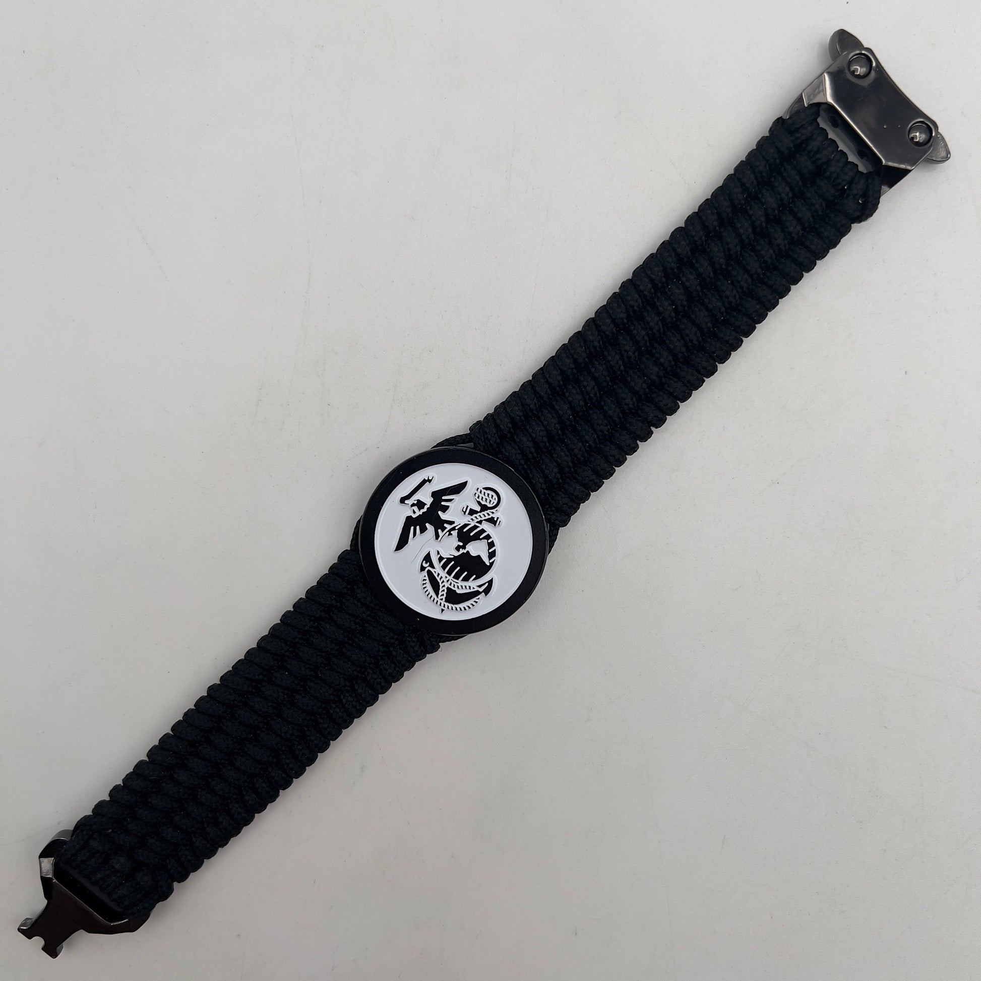 Thin, medium width, flexible and comfortable braided United States Marine Corps bracelet featuring a black USMC Eagle Globe and Anchor medallion, a black Cobra style tactical buckle and woven with black Type-1 paracord.