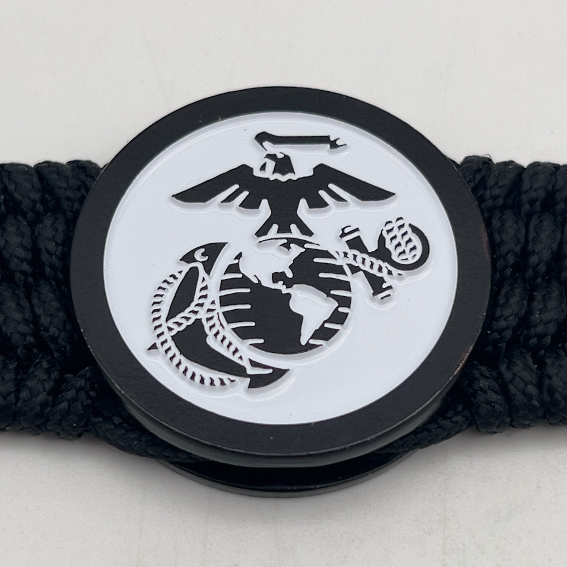 Thin, medium width, flexible and comfortable braided United States Marine Corps bracelet featuring a black USMC Eagle Globe and Anchor medallion, a black Cobra style tactical buckle and woven with black Type-1 paracord.