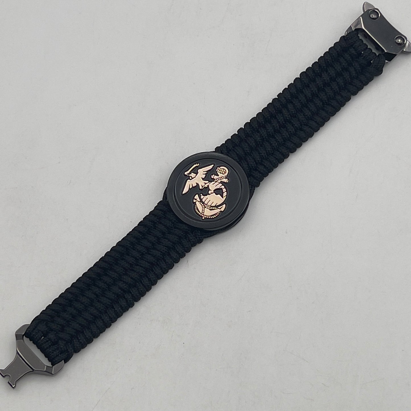 Thin, medium width, flexible and comfortable braided United States Marine Corps bracelet featuring a 24K gold USMC Eagle Globe and Anchor medallion, a black Cobra style tactical buckle and woven with black Type-1 paracord.