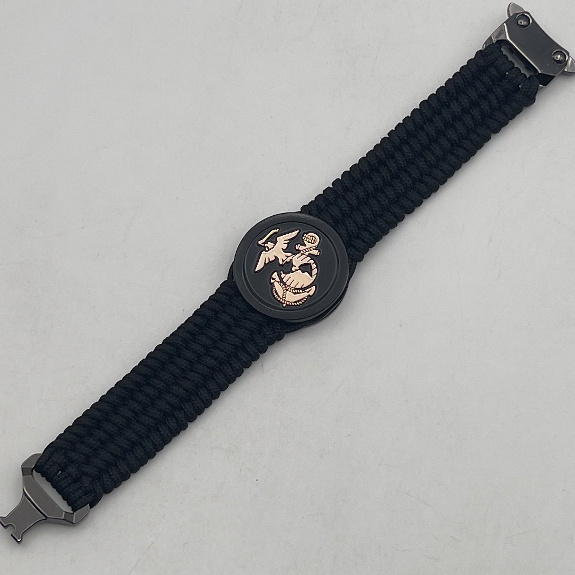 Thin, medium width, flexible and comfortable braided United States Marine Corps bracelet featuring a 24K gold USMC Eagle Globe and Anchor medallion, a black Cobra style tactical buckle and woven with black Type-1 paracord.