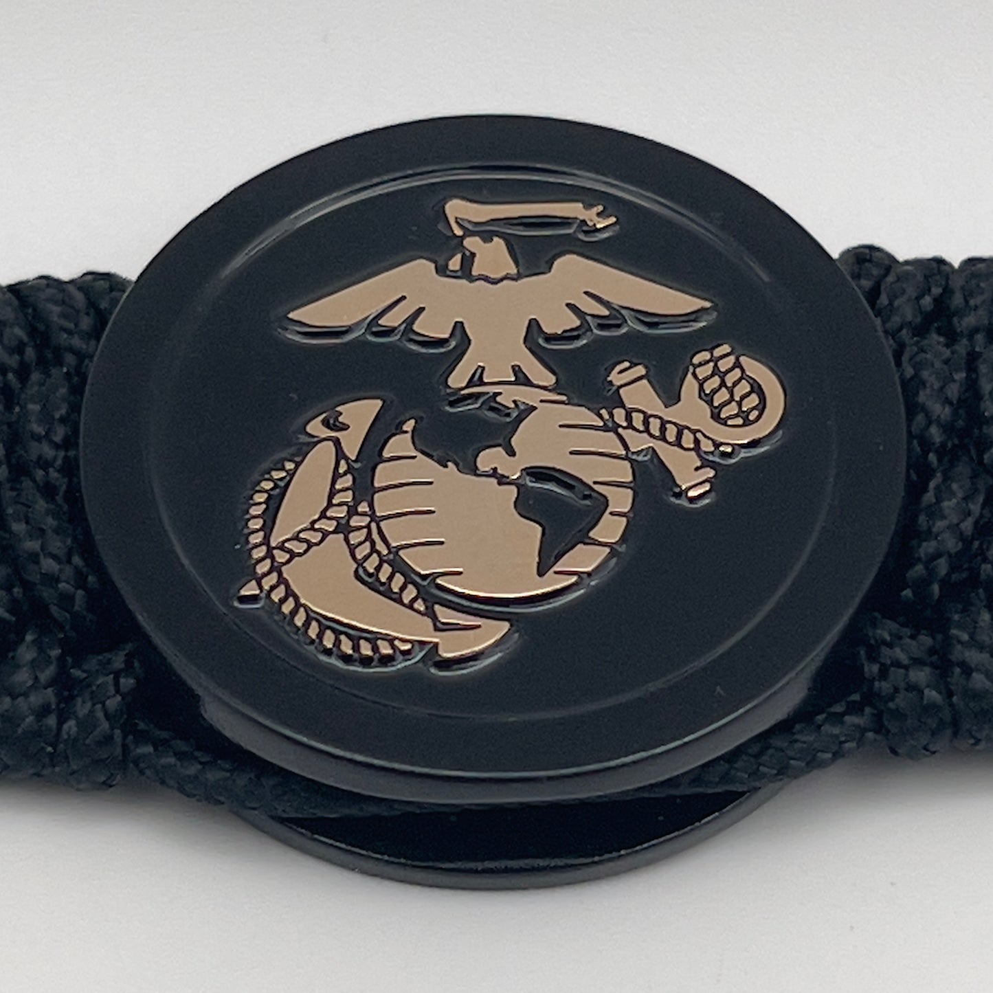 Thin, medium width, flexible and comfortable braided United States Marine Corps bracelet featuring a 24K gold USMC Eagle Globe and Anchor medallion, a black Cobra style tactical buckle and woven with black Type-1 paracord.