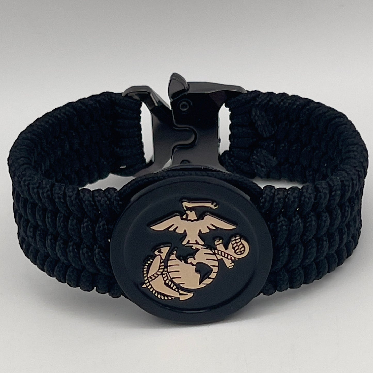 Thin, medium width, flexible and comfortable braided United States Marine Corps bracelet featuring a 24K gold USMC Eagle Globe and Anchor medallion, a black Cobra style tactical buckle and woven with black Type-1 paracord.