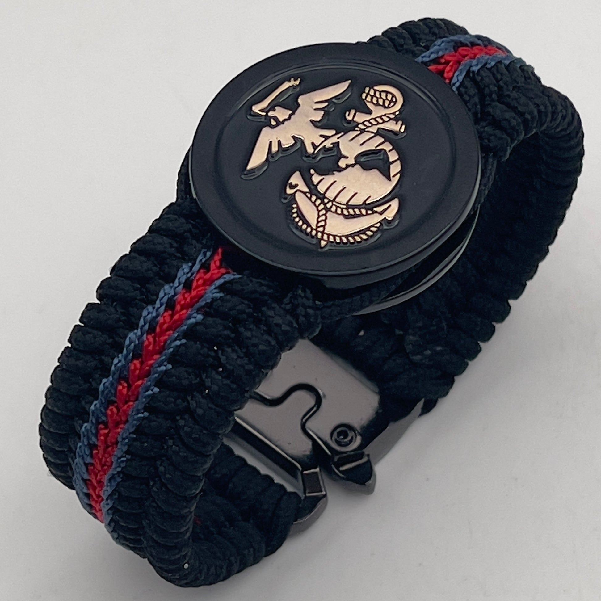 Thin, medium width, flexible and comfortable braided United States Marine Corps bracelet featuring a black USMC Eagle Globe and Anchor medallion, a black Cobra style tactical buckle and woven with black Type-1 paracord and blue and red nano cord.