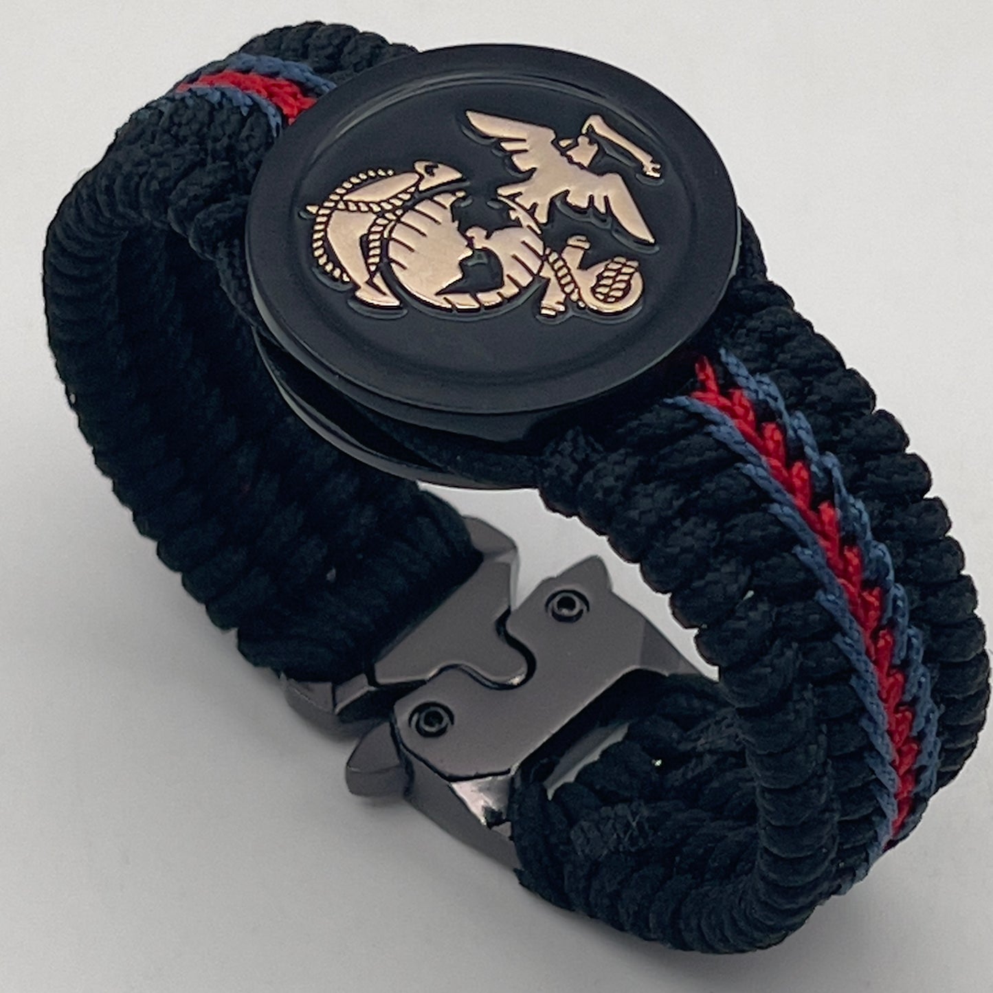 Thin, medium width, flexible and comfortable braided United States Marine Corps bracelet featuring a black USMC Eagle Globe and Anchor medallion, a black Cobra style tactical buckle and woven with black Type-1 paracord and blue and red nano cord.