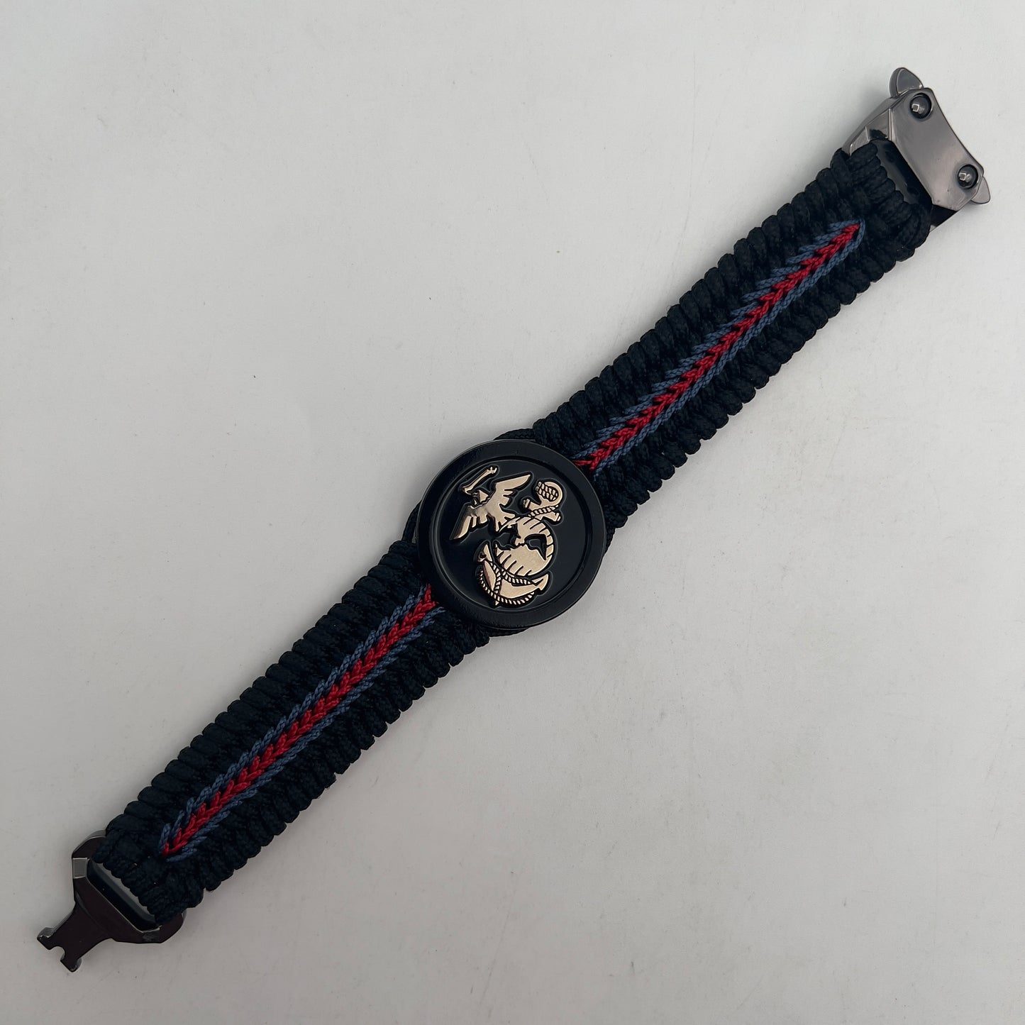 Thin, medium width, flexible and comfortable braided United States Marine Corps bracelet featuring a black USMC Eagle Globe and Anchor medallion, a black Cobra style tactical buckle and woven with black Type-1 paracord and blue and red nano cord.