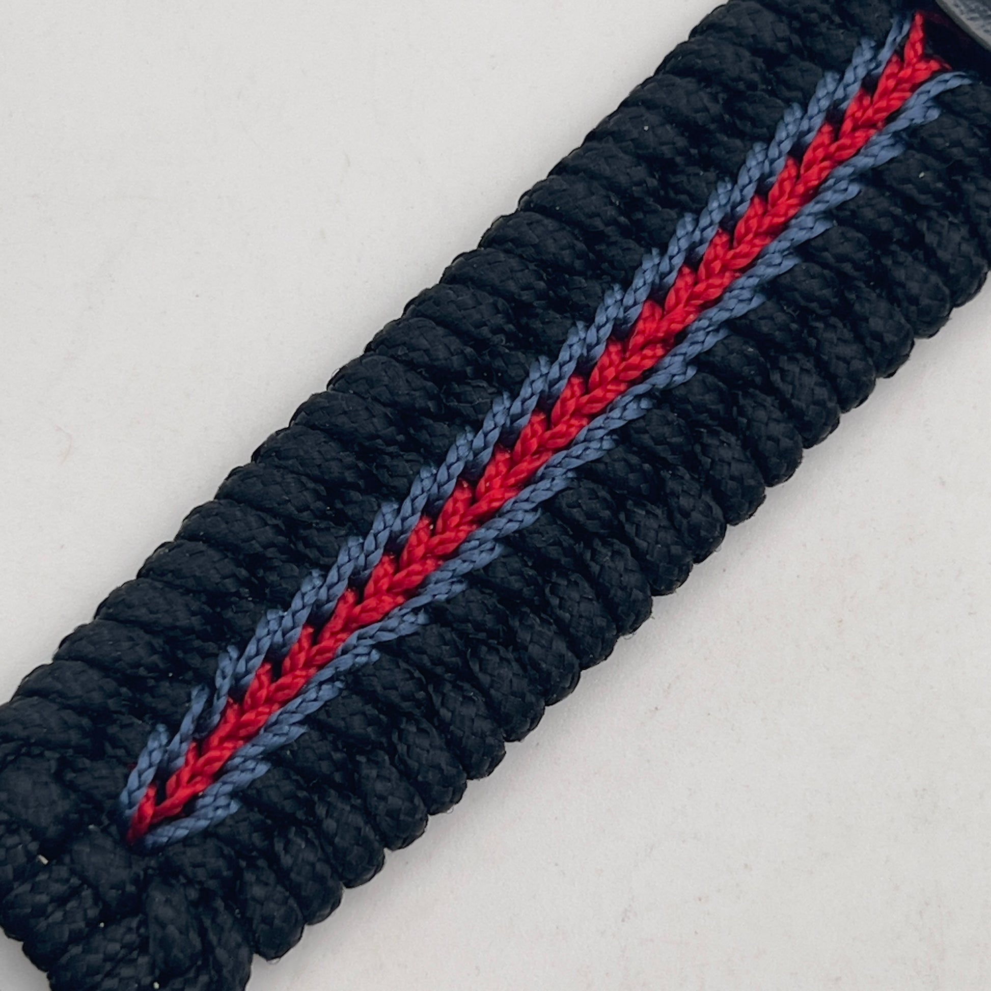 Thin, medium width, flexible and comfortable braided United States Marine Corps bracelet featuring a black USMC Eagle Globe and Anchor medallion, a black Cobra style tactical buckle and woven with black Type-1 paracord and blue and red nano cord.