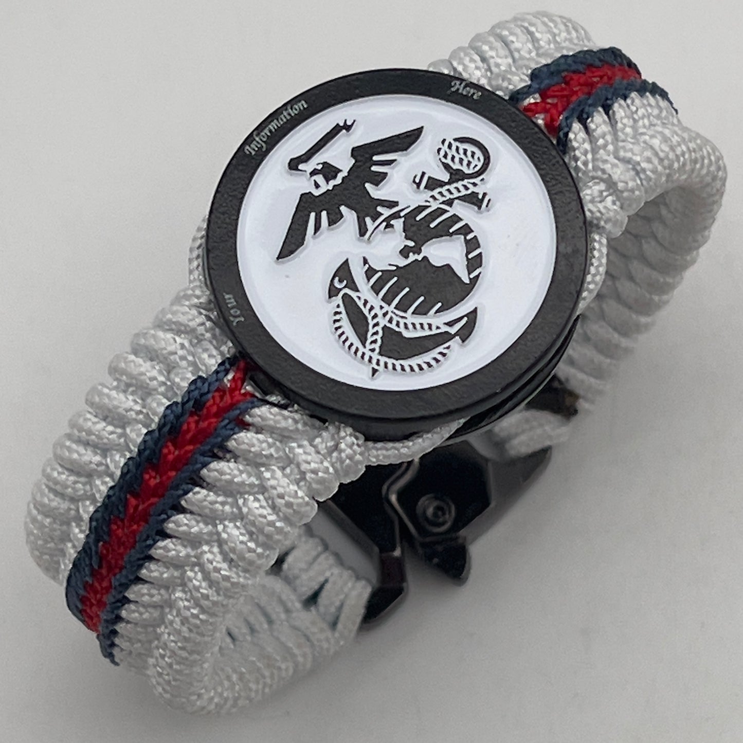 Thin, medium width, flexible and comfortable braided United States Marine Corps bracelet featuring a black USMC Eagle Globe and Anchor medallion, a black Cobra style tactical buckle and woven with white Type-1 paracord and stitched with red and blue nano cord.