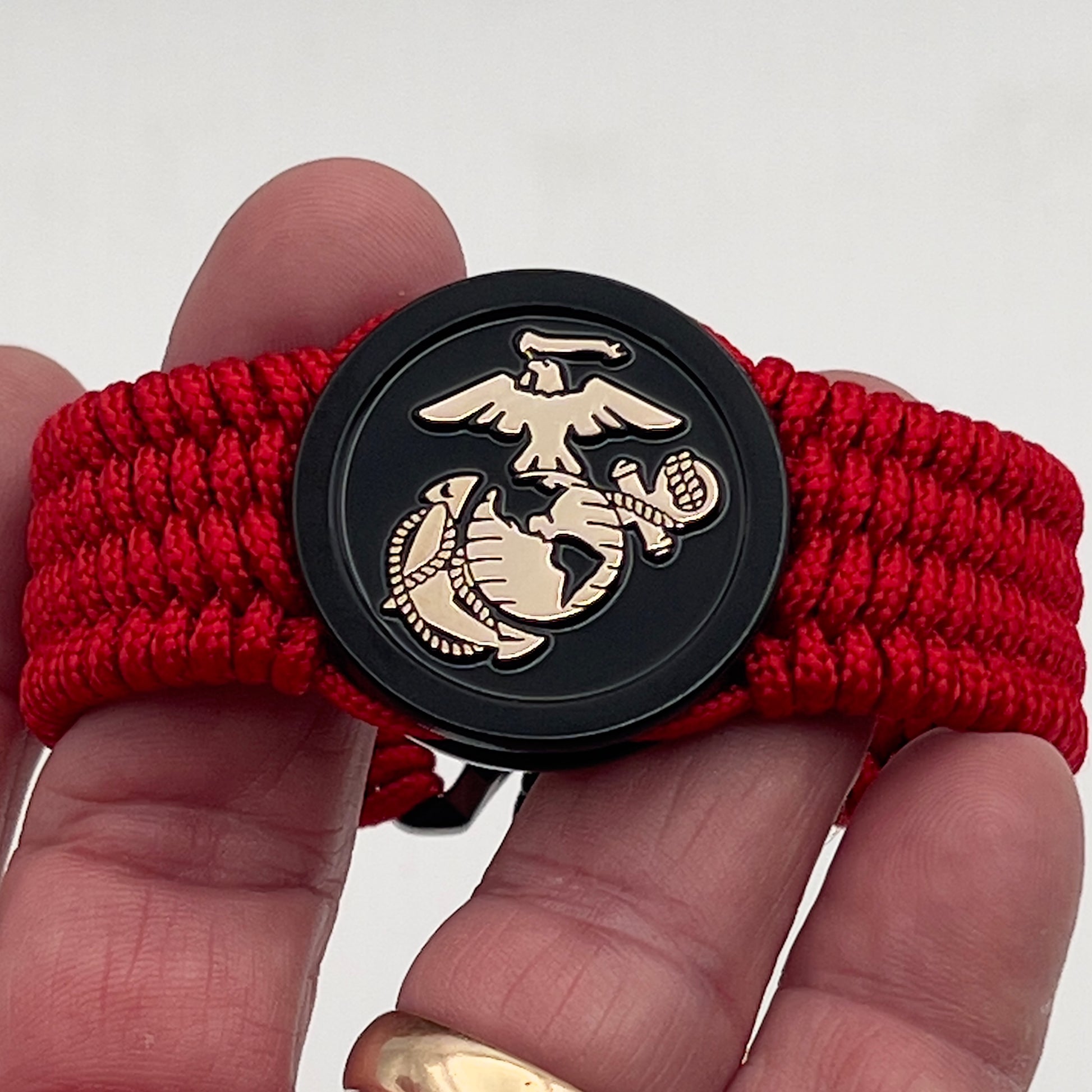 Thin, medium width, flexible and comfortable braided United States Marine Corps bracelet featuring a 24K gold USMC Eagle Globe and Anchor medallion, a black Cobra style tactical buckle and woven with red Type-1 paracord.