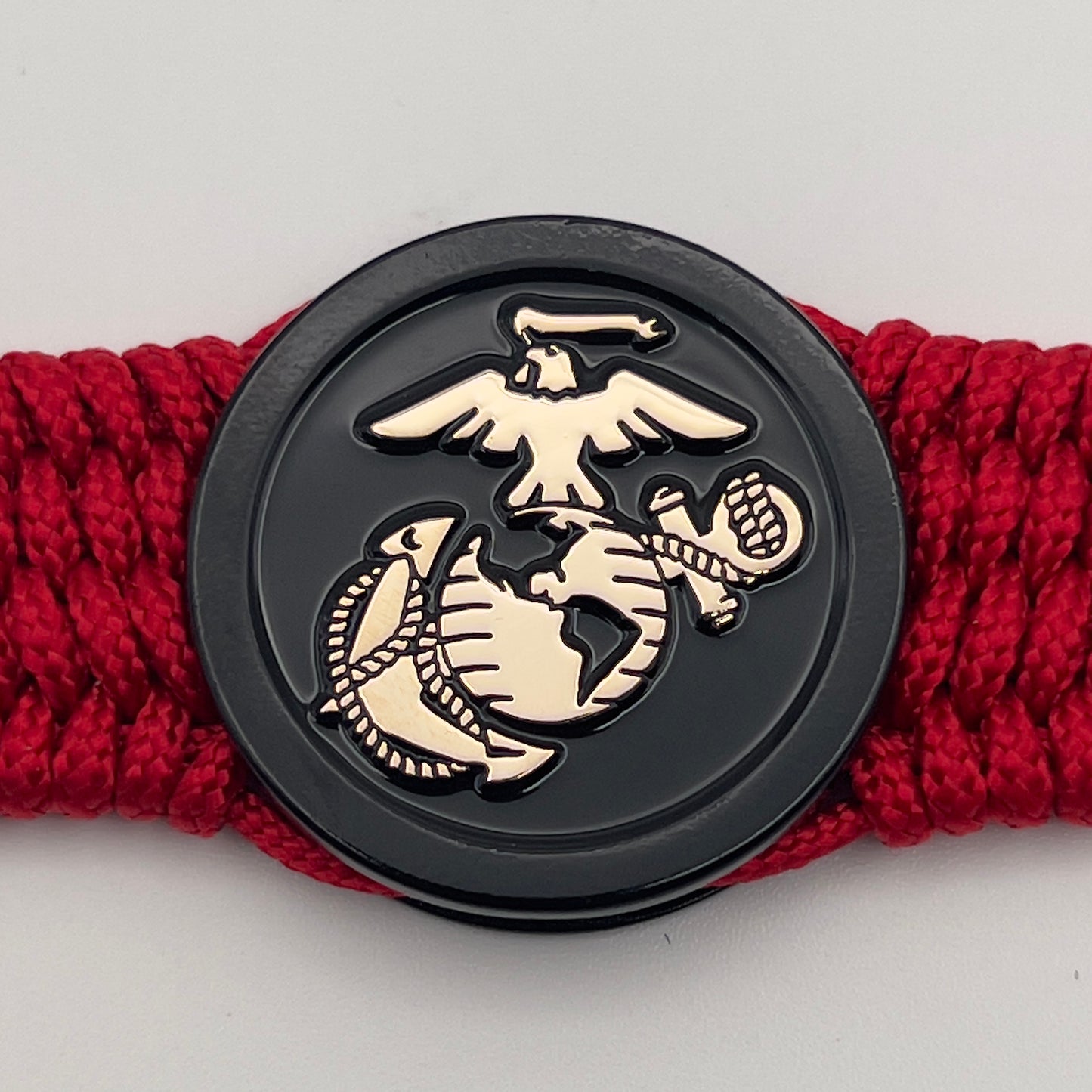 Thin, medium width, flexible and comfortable braided United States Marine Corps bracelet featuring a 24K gold USMC Eagle Globe and Anchor medallion, a black Cobra style tactical buckle and woven with red Type-1 paracord.