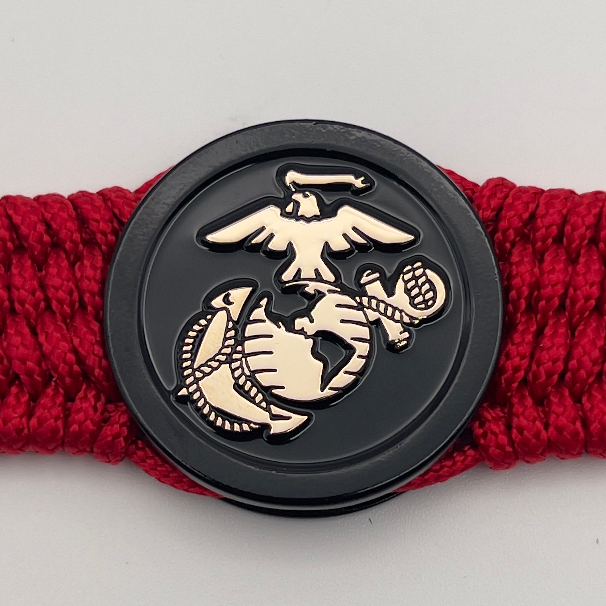 Thin, medium width, flexible and comfortable braided United States Marine Corps bracelet featuring a 24K gold USMC Eagle Globe and Anchor medallion, a black Cobra style tactical buckle and woven with red Type-1 paracord.