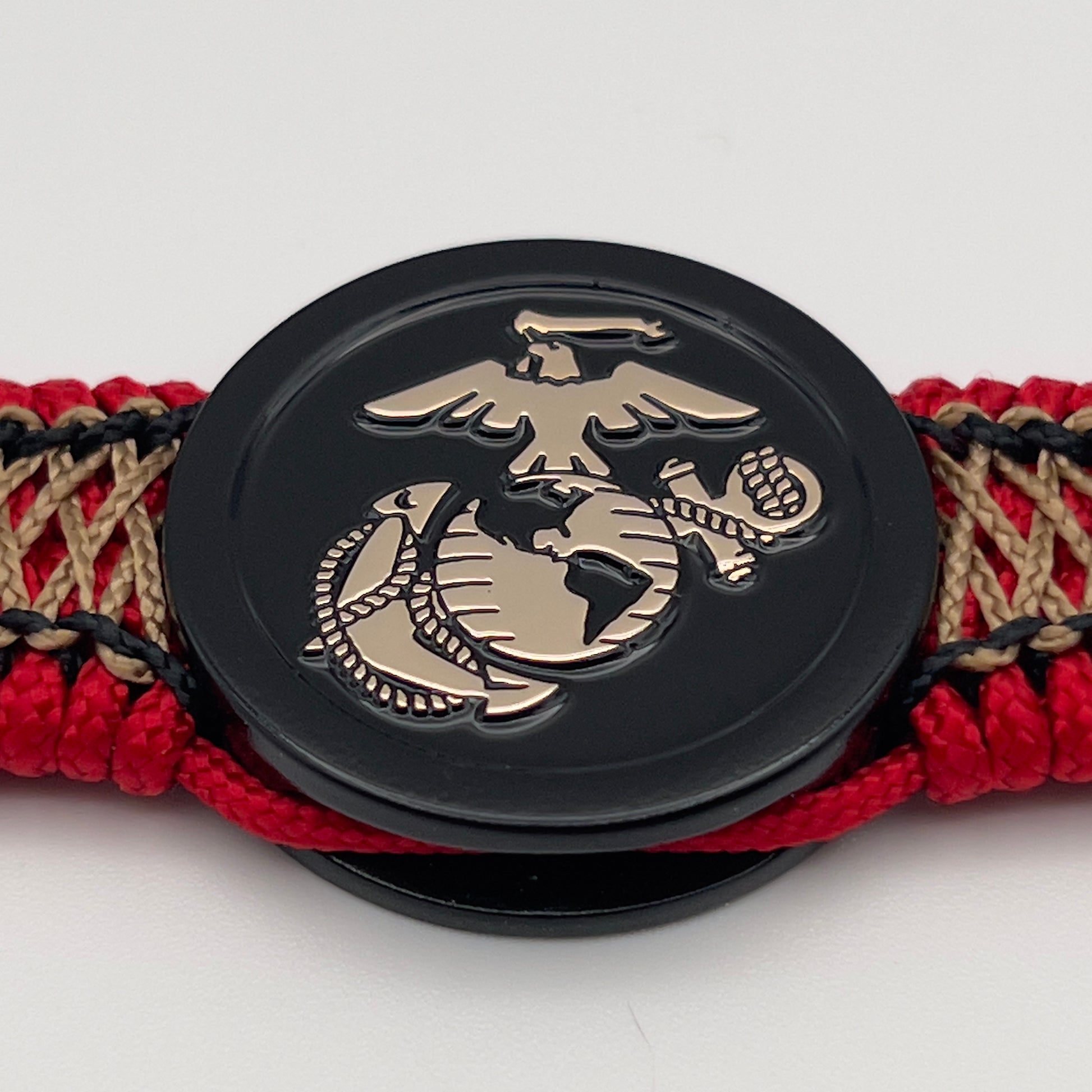 Thin, narrow, flexible and comfortable braided United States Marine Corps bracelet featuring the official US Marine Corps Eagle, Globe and Anchor medallion, a black Cobra style tactical buckle and woven with red Type-1 paracord and center stitched with black and gold nano cord.