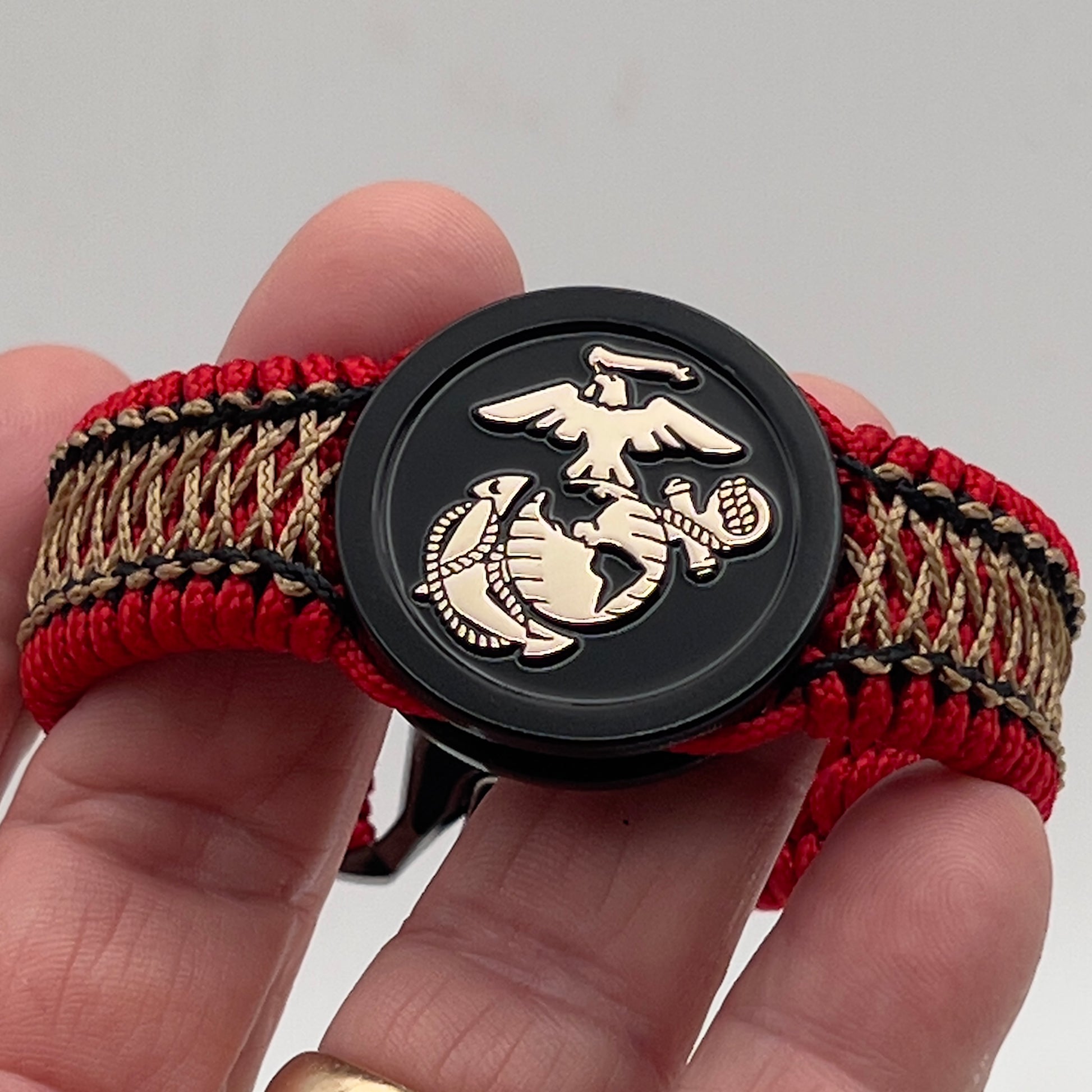 Thin, narrow, flexible and comfortable braided United States Marine Corps bracelet featuring the official US Marine Corps Eagle, Globe and Anchor medallion, a black Cobra style tactical buckle and woven with red Type-1 paracord and center stitched with black and gold nano cord.