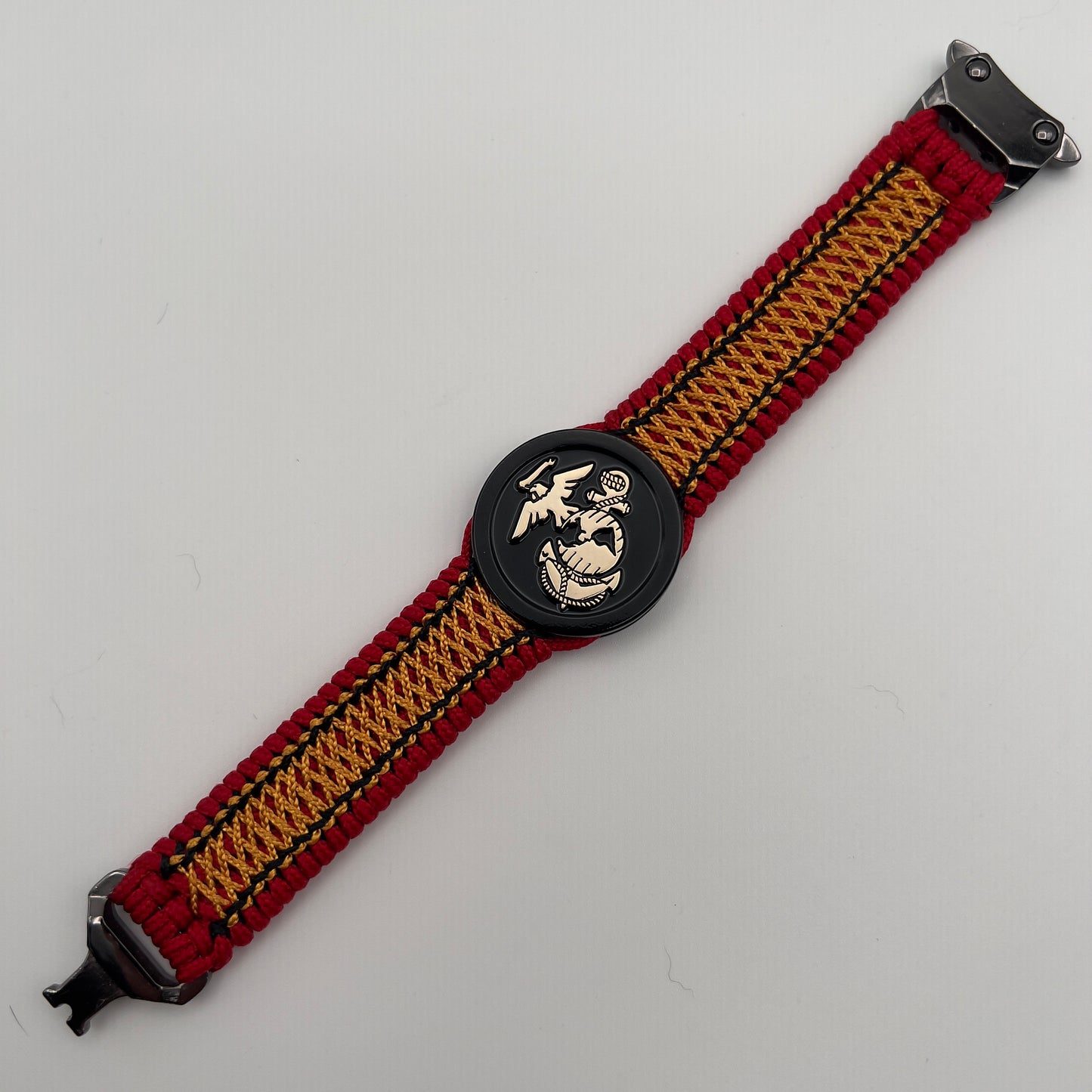 Thin, narrow, flexible and comfortable braided United States Marine Corps bracelet featuring the official US Marine Corps Eagle, Globe and Anchor medallion, a black Cobra style tactical buckle and woven with red Type-1 paracord and center stitched with black and goldenrod nano cord.