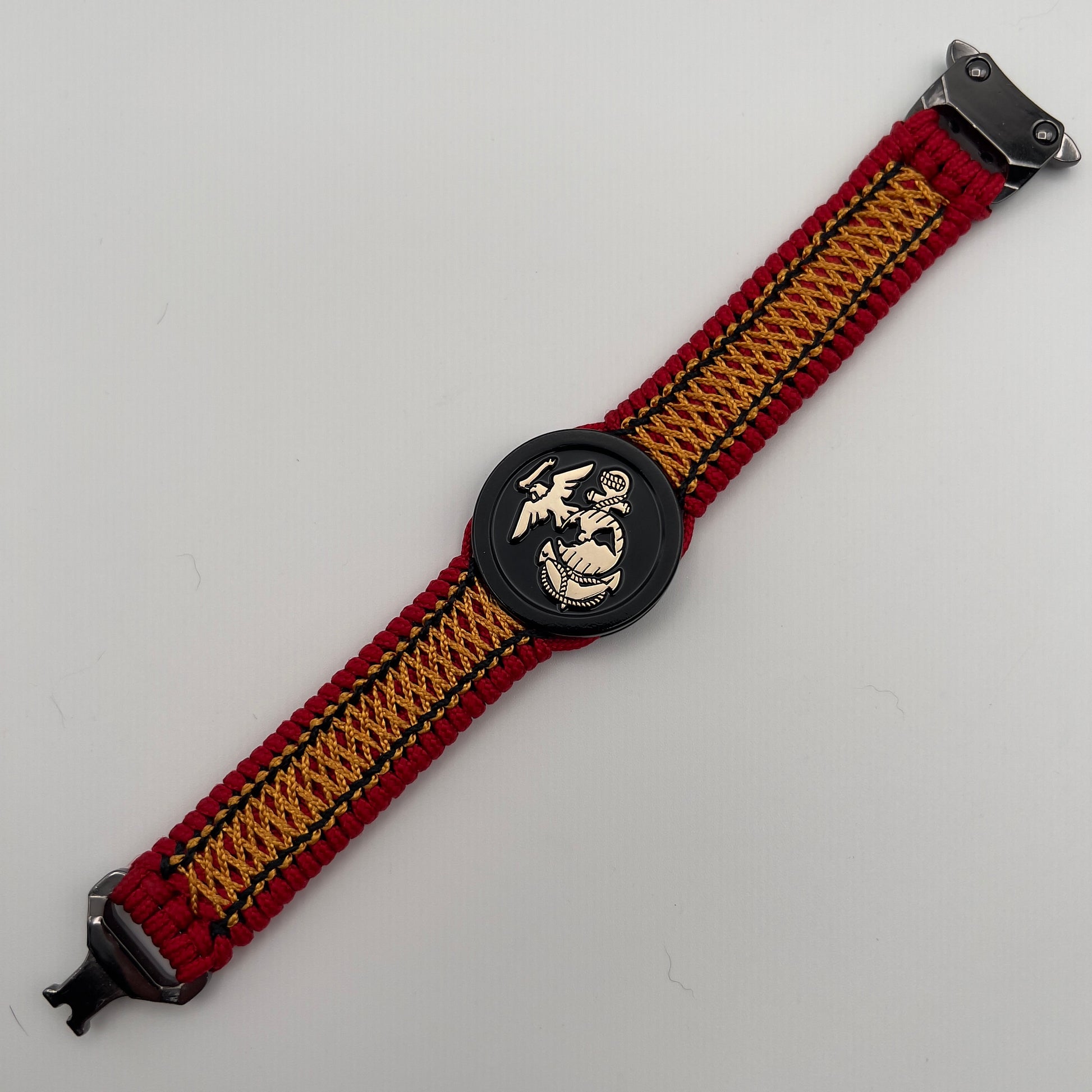 Thin, narrow, flexible and comfortable braided United States Marine Corps bracelet featuring the official US Marine Corps Eagle, Globe and Anchor medallion, a black Cobra style tactical buckle and woven with red Type-1 paracord and center stitched with black and goldenrod nano cord.