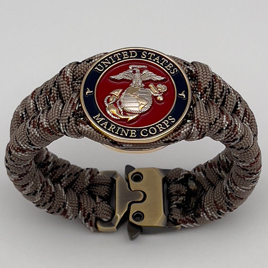 Thick and comfortable braided United States Marine Corps bracelet featuring a 24K gold and silver plated USMC officer Eagle Globe and Anchor medallion, a Cobra style tactical buckle and woven with Desert Camo paracord.