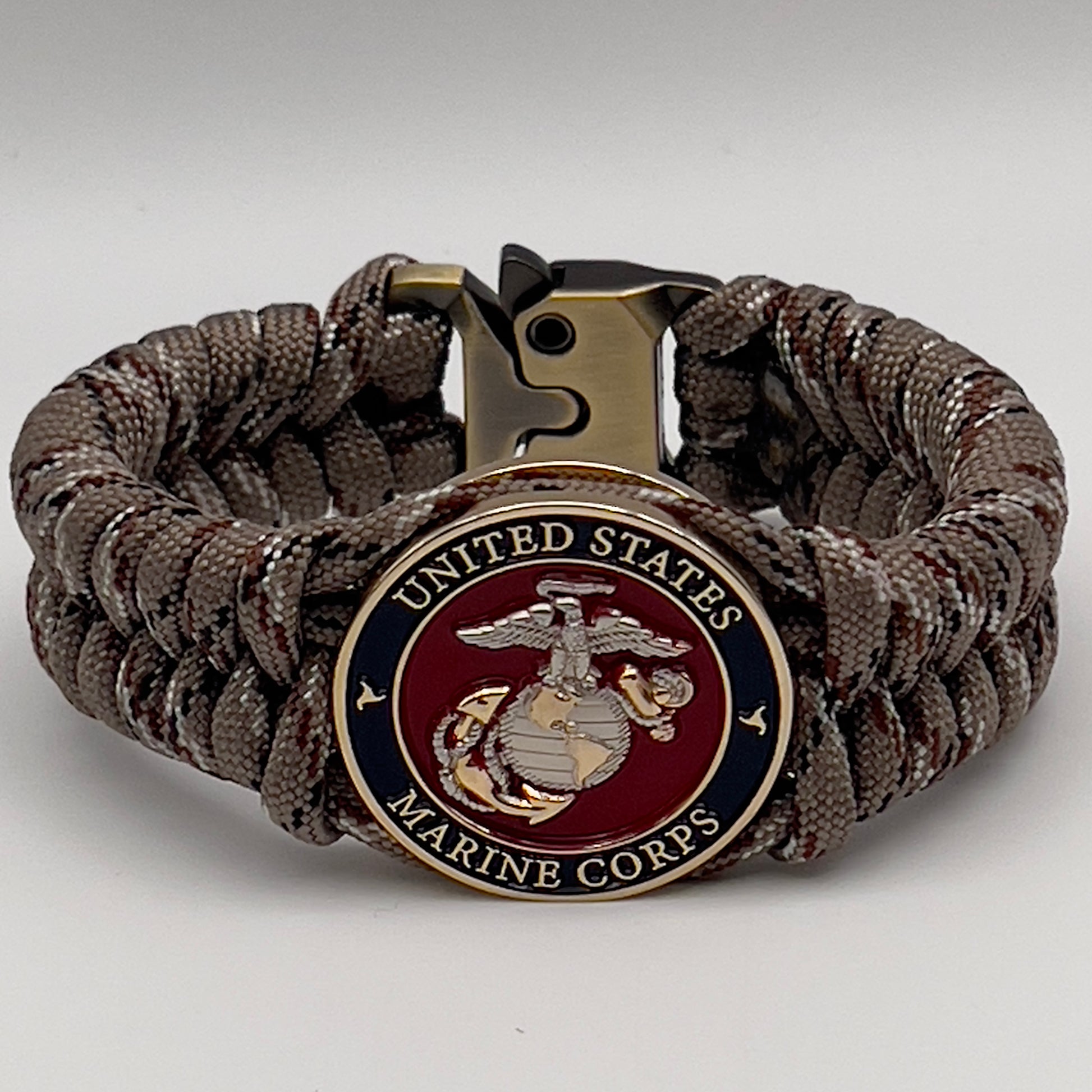 Thick and comfortable braided United States Marine Corps bracelet featuring a 24K gold and silver plated USMC officer Eagle Globe and Anchor medallion, a Cobra style tactical buckle and woven with Desert Camo paracord.