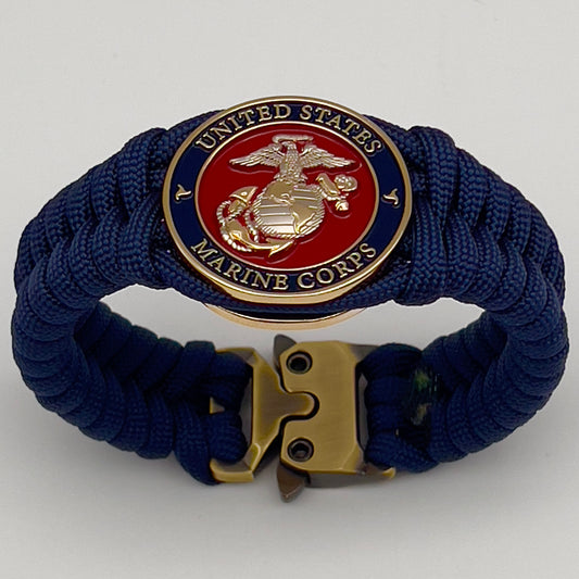 Thick and comfortable braided United States Marine Corps bracelet featuring a 24K gold and silver plated USMC officer Eagle Globe and Anchor medallion, a Cobra style tactical buckle and woven with Navy blue paracord.