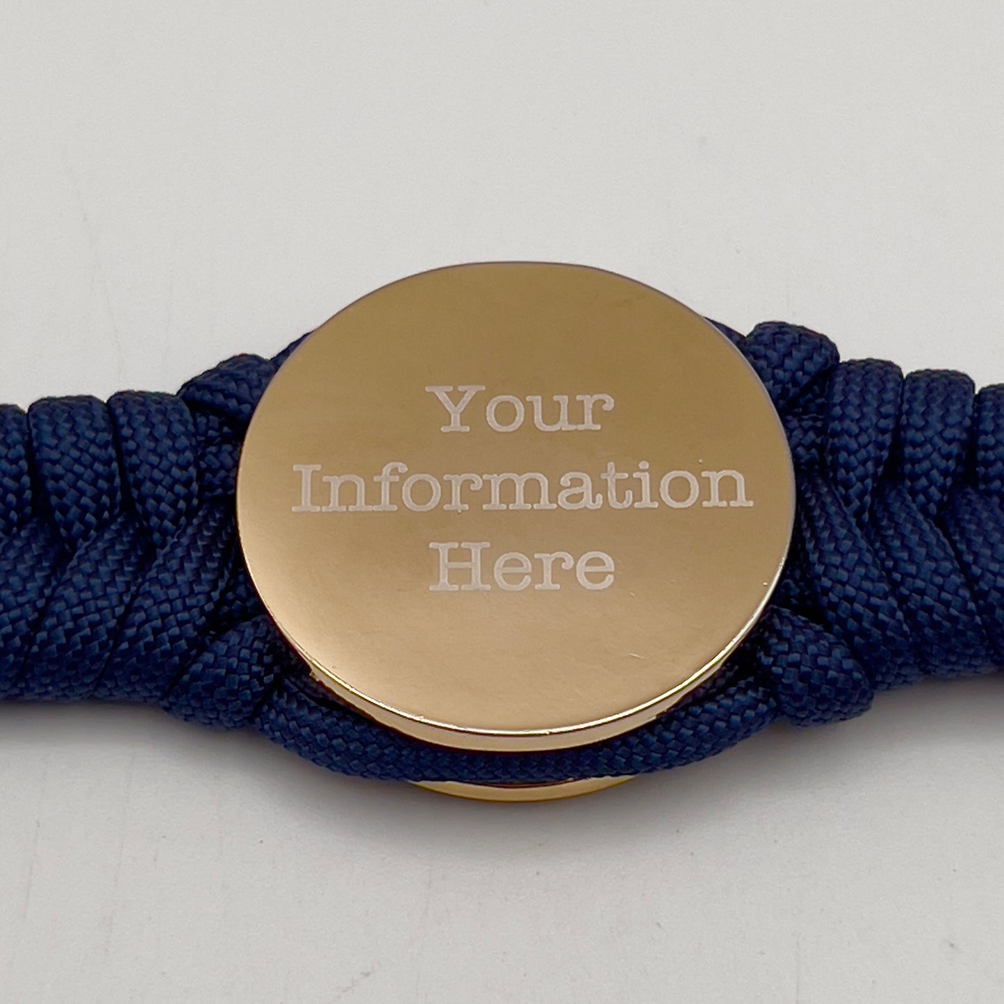 Thick and comfortable braided United States Marine Corps bracelet featuring a 24K gold and silver plated USMC officer Eagle Globe and Anchor medallion, a Cobra style tactical buckle and woven with Navy blue paracord.