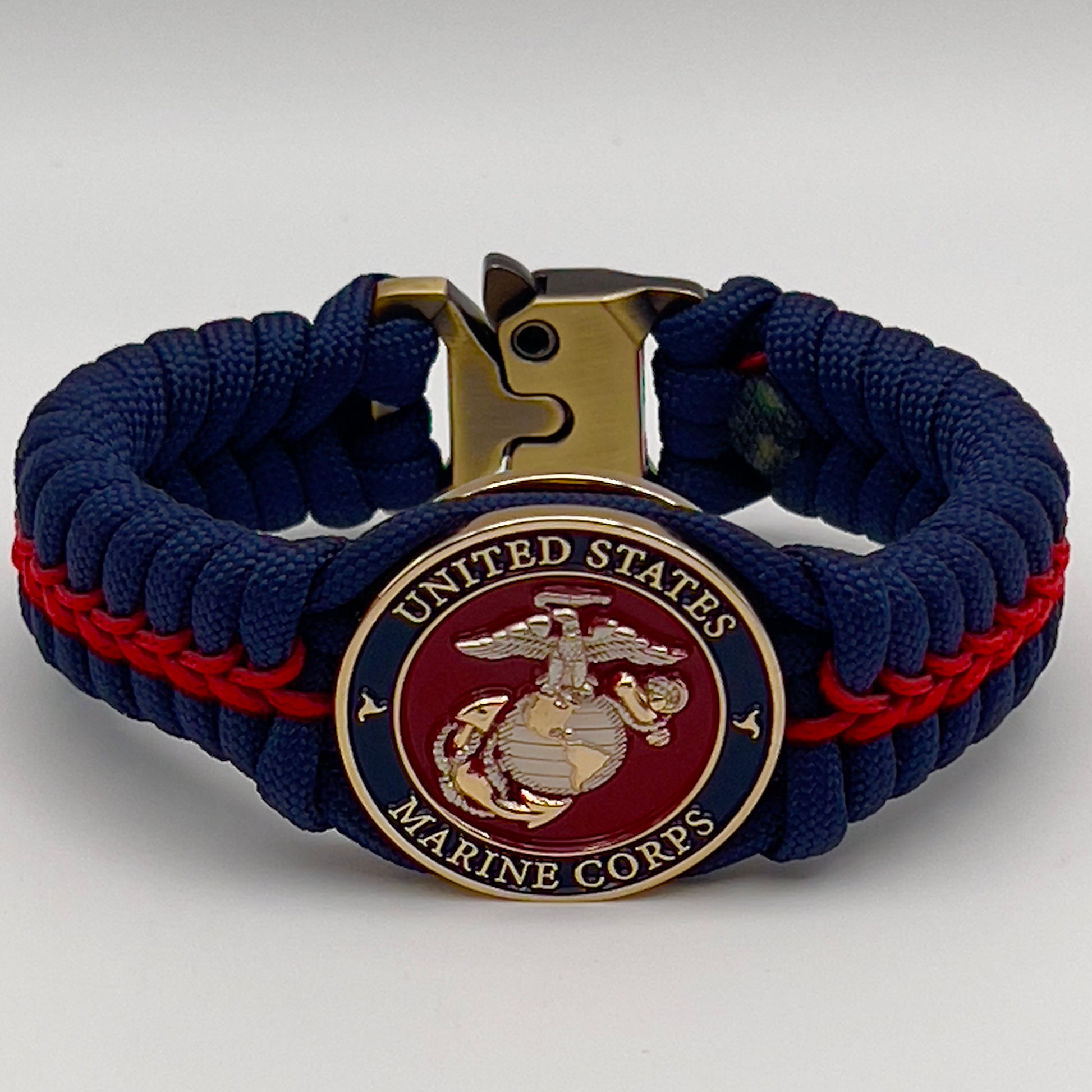 Thick and comfortable braided United States Marine Corps bracelet featuring a 24K gold and silver plated USMC officer Eagle Globe and Anchor medallion, a Cobra style tactical buckle and woven with Navy blue and Imperial red paracord.