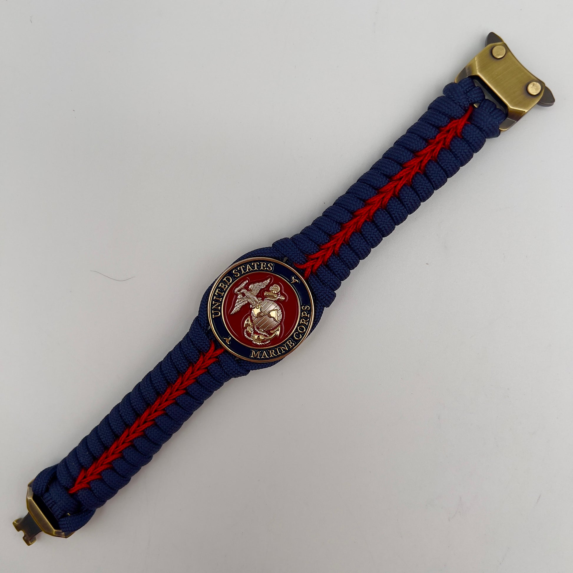 Thick and comfortable braided United States Marine Corps bracelet featuring a 24K gold and silver plated USMC officer Eagle Globe and Anchor medallion, a Cobra style tactical buckle and woven with Navy blue and Imperial red paracord.