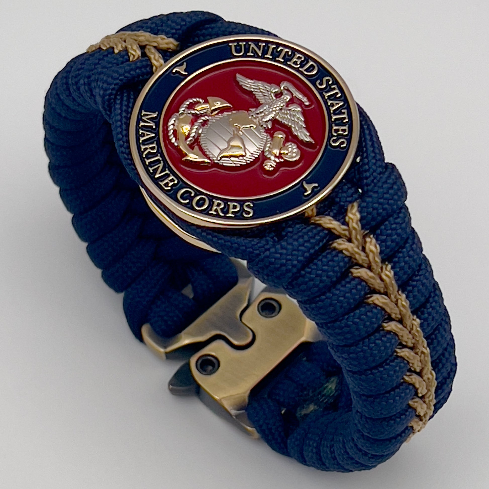 Thick and comfortable braided United States Marine Corps bracelet featuring a 24K gold and silver plated USMC officer Eagle Globe and Anchor medallion, a Cobra style tactical buckle and woven with Navy blue and gold paracord.