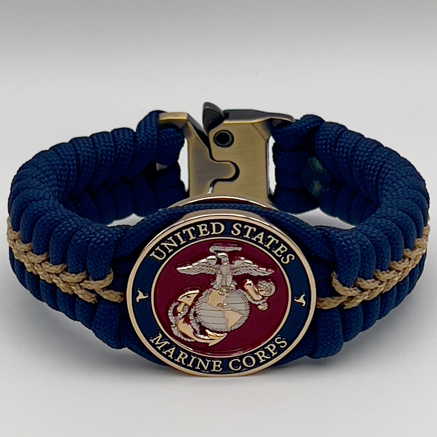 Thick and comfortable braided United States Marine Corps bracelet featuring a 24K gold and silver plated USMC officer Eagle Globe and Anchor medallion, a Cobra style tactical buckle and woven with Navy blue and gold paracord.