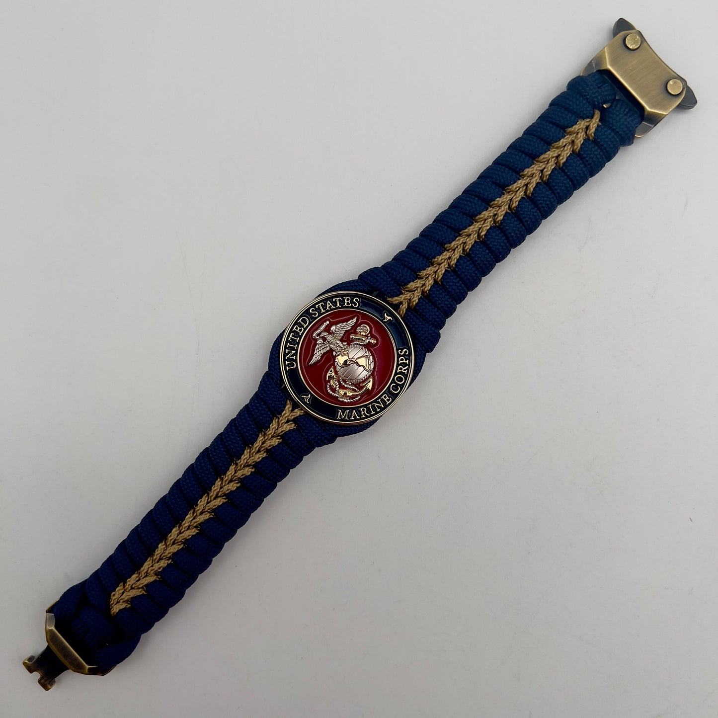 Thick and comfortable braided United States Marine Corps bracelet featuring a 24K gold and silver plated USMC officer Eagle Globe and Anchor medallion, a Cobra style tactical buckle and woven with Navy blue and gold paracord.