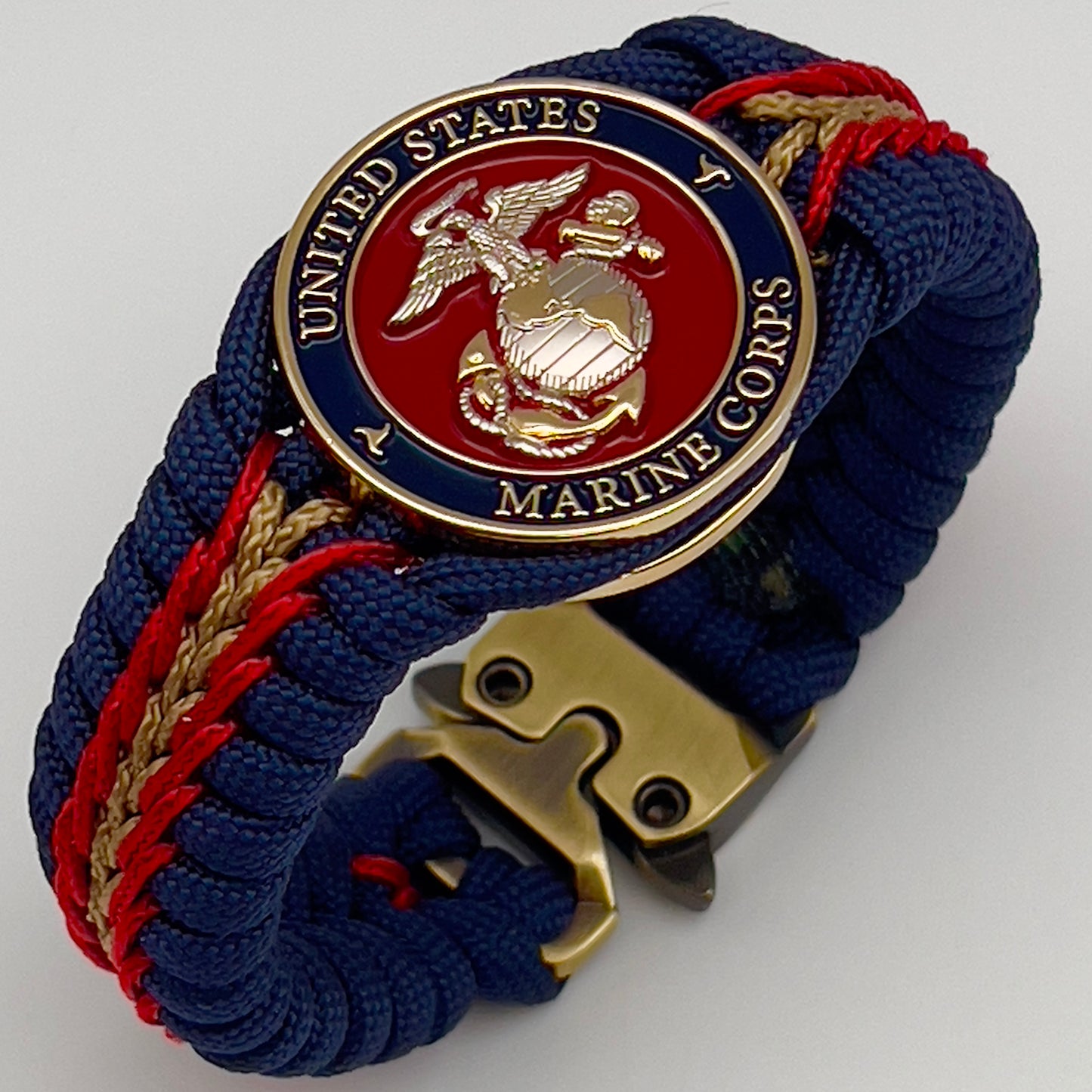 Thick and comfortable braided United States Marine Corps bracelet featuring a 24K gold and silver plated USMC officer Eagle Globe and Anchor medallion, a Cobra style tactical buckle and woven with Navy blue, Imperial red and gold paracord.