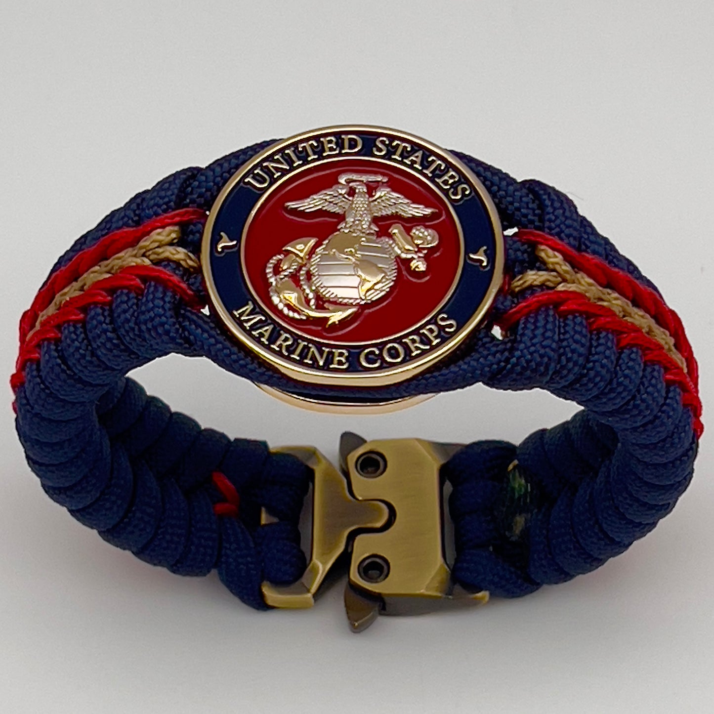 Thick and comfortable braided United States Marine Corps bracelet featuring a 24K gold and silver plated USMC officer Eagle Globe and Anchor medallion, a Cobra style tactical buckle and woven with Navy blue, Imperial red and gold paracord.