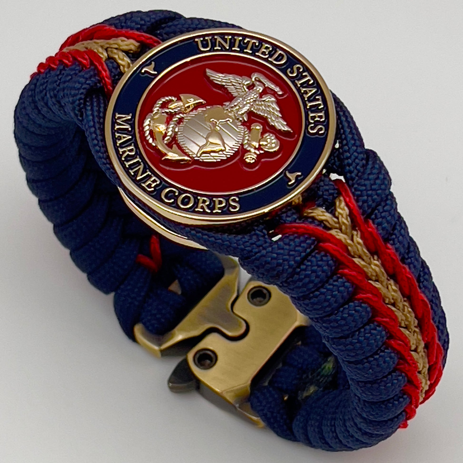 Thick and comfortable braided United States Marine Corps bracelet featuring a 24K gold and silver plated USMC officer Eagle Globe and Anchor medallion, a Cobra style tactical buckle and woven with Navy blue, Imperial red and gold paracord.