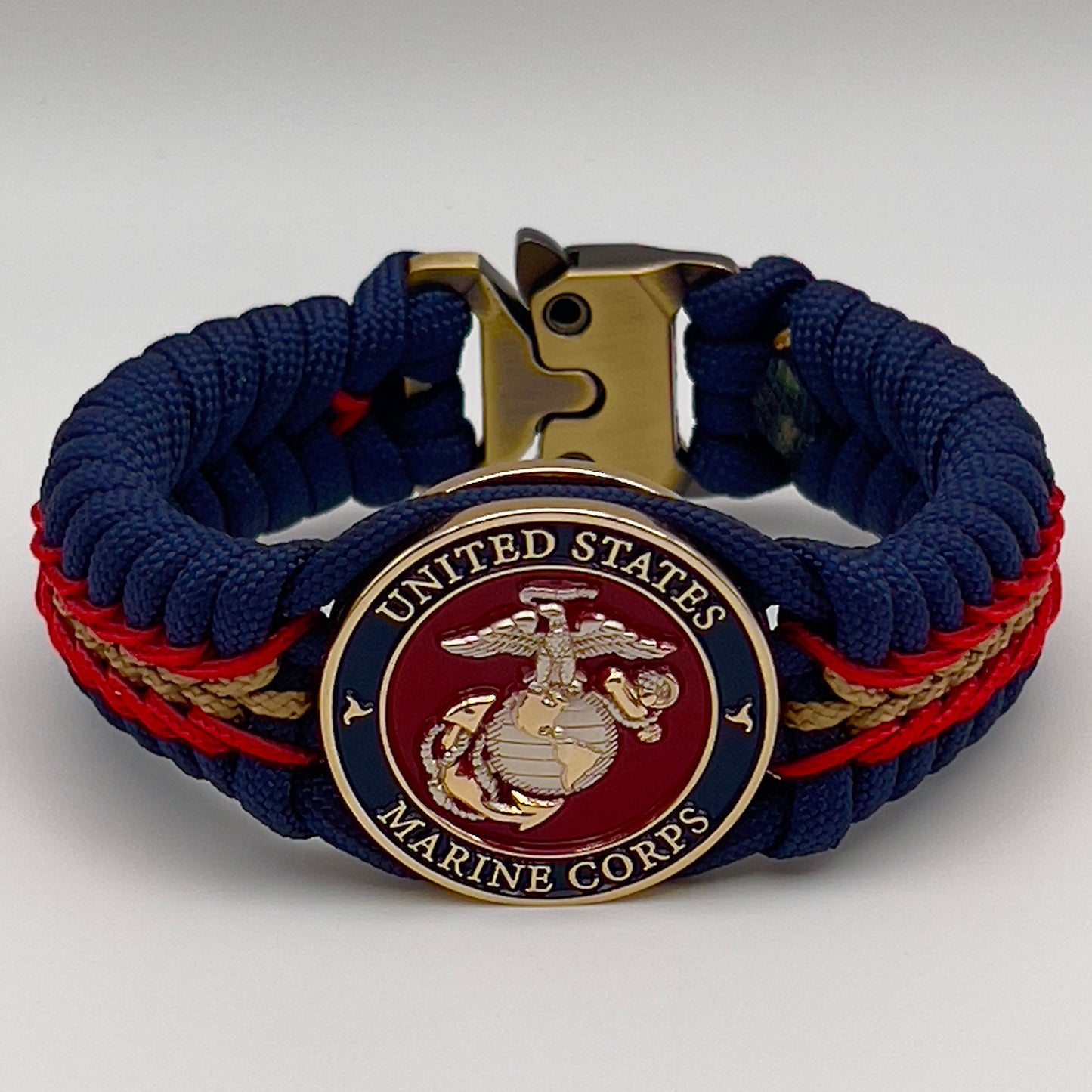 Thick and comfortable braided United States Marine Corps bracelet featuring a 24K gold and silver plated USMC officer Eagle Globe and Anchor medallion, a Cobra style tactical buckle and woven with Navy blue, Imperial red and gold paracord.