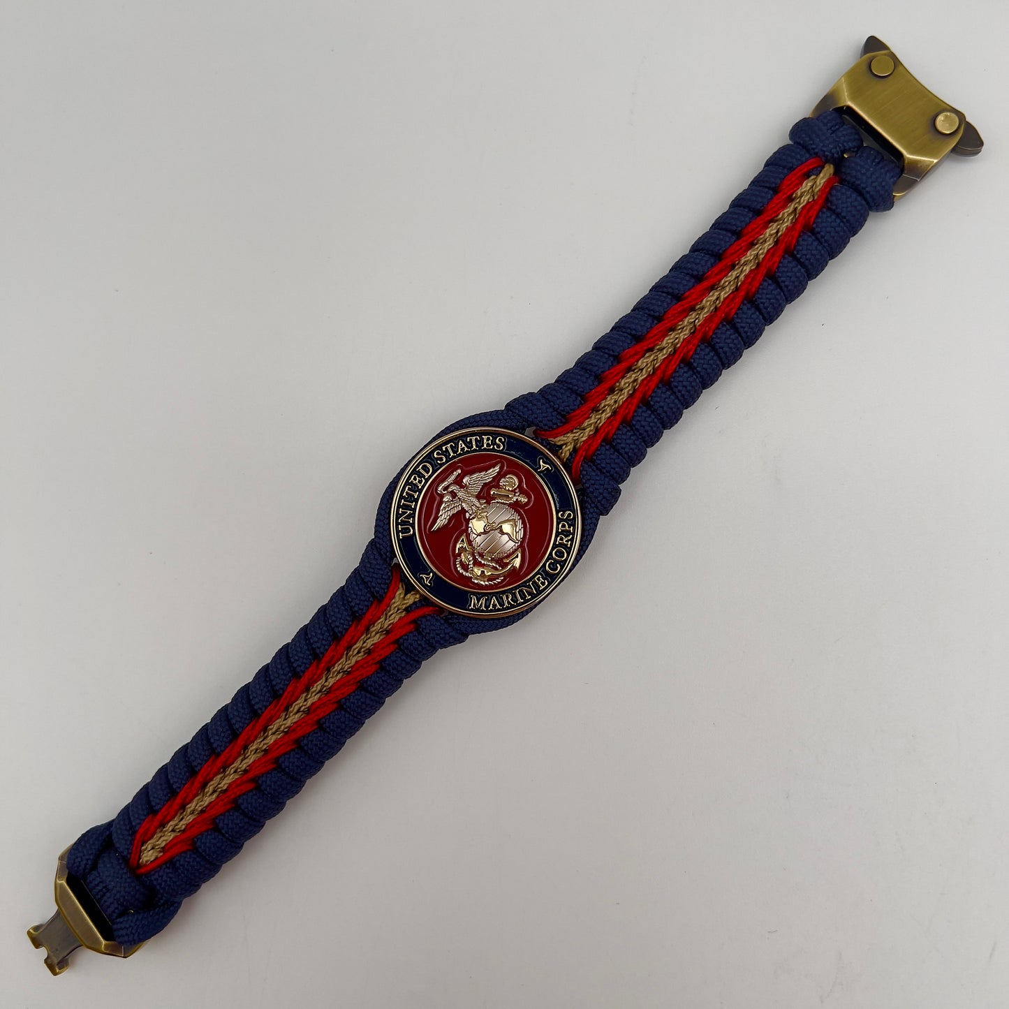 Thick and comfortable braided United States Marine Corps bracelet featuring a 24K gold and silver plated USMC officer Eagle Globe and Anchor medallion, a Cobra style tactical buckle and woven with Navy blue, Imperial red and gold paracord.