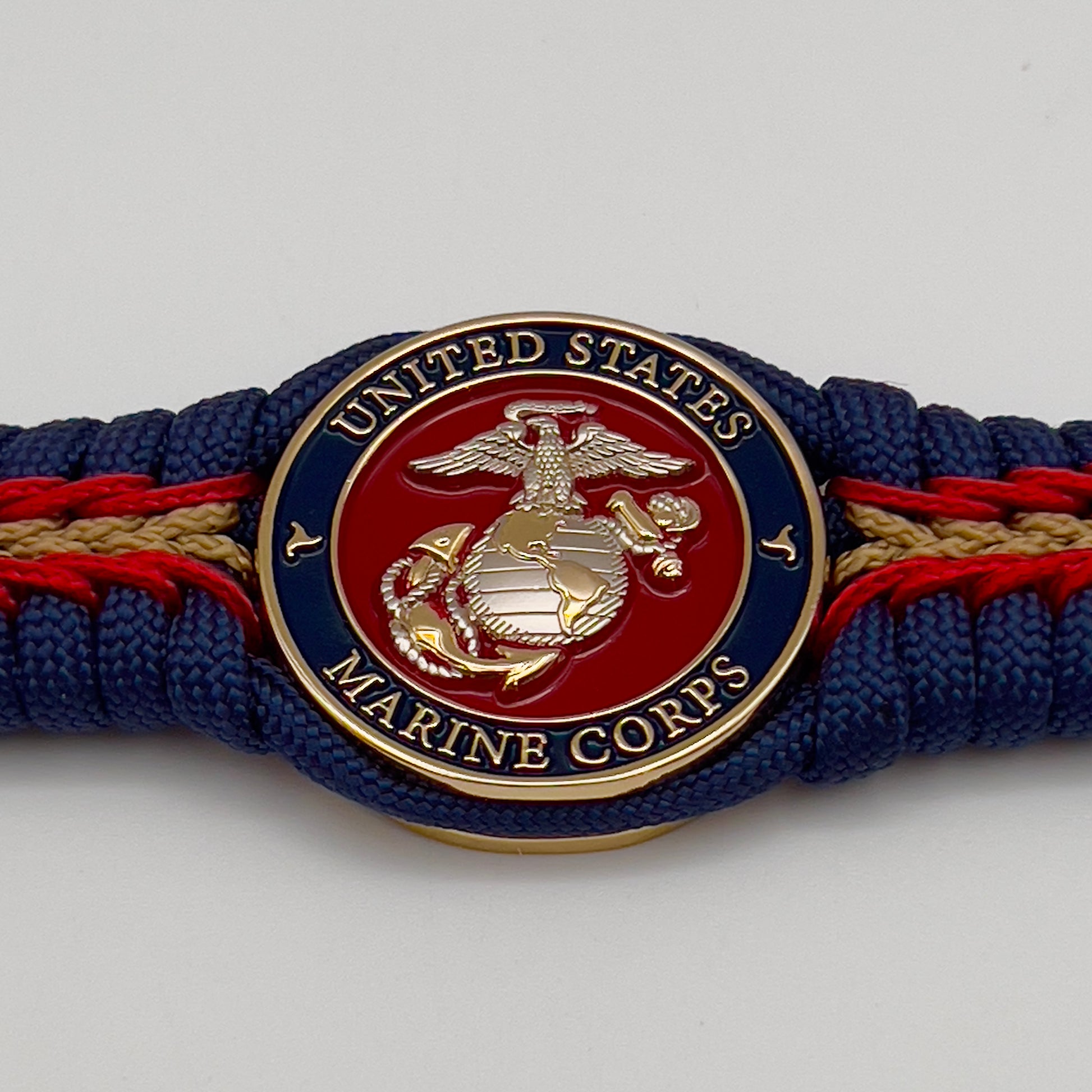 Thick and comfortable braided United States Marine Corps bracelet featuring a 24K gold and silver plated USMC officer Eagle Globe and Anchor medallion, a Cobra style tactical buckle and woven with Navy blue, Imperial red and gold paracord.