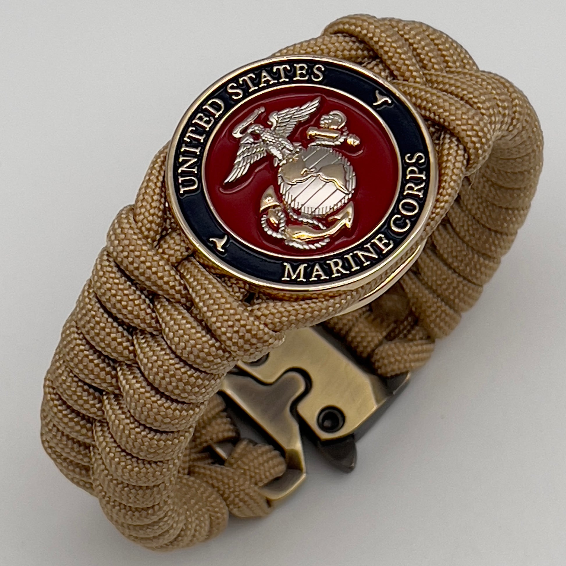 Thick and comfortable braided United States Marine Corps bracelet featuring a 24K gold and silver plated USMC officer Eagle Globe and Anchor medallion, a Cobra style tactical buckle and woven with gold 550 paracord.