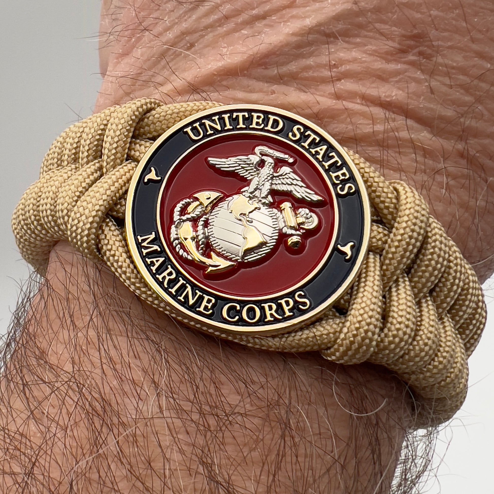 Thick and comfortable braided United States Marine Corps bracelet featuring a 24K gold and silver plated USMC officer Eagle Globe and Anchor medallion, a Cobra style tactical buckle and woven with gold 550 paracord.