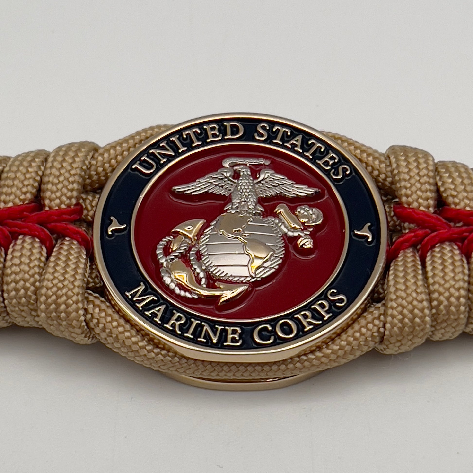 Thick and comfortable braided United States Marine Corps bracelet featuring a 24K gold and silver plated USMC officer Eagle Globe and Anchor medallion, a Cobra style tactical buckle and woven with gold 550 and Imperial red micro paracord.