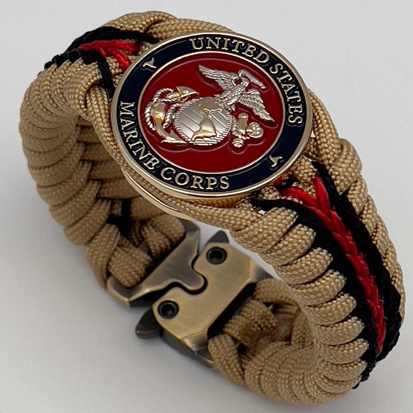 Thick and comfortable braided United States Marine Corps bracelet featuring a 24K gold and silver plated USMC officer Eagle Globe and Anchor medallion, a Cobra style tactical buckle and woven with gold 550 and Imperial red micro paracord.