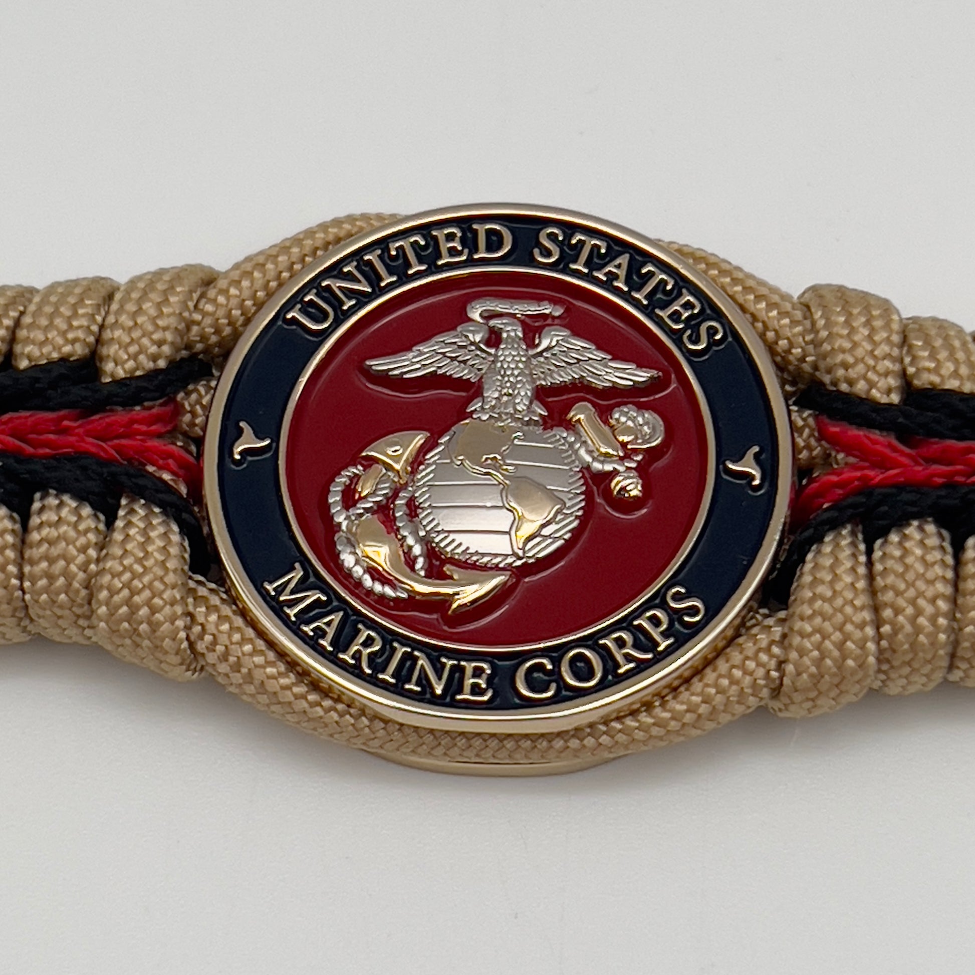 Thick and comfortable braided United States Marine Corps bracelet featuring a 24K gold and silver plated USMC officer Eagle Globe and Anchor medallion, a Cobra style tactical buckle and woven with gold 550 and Imperial red micro paracord.