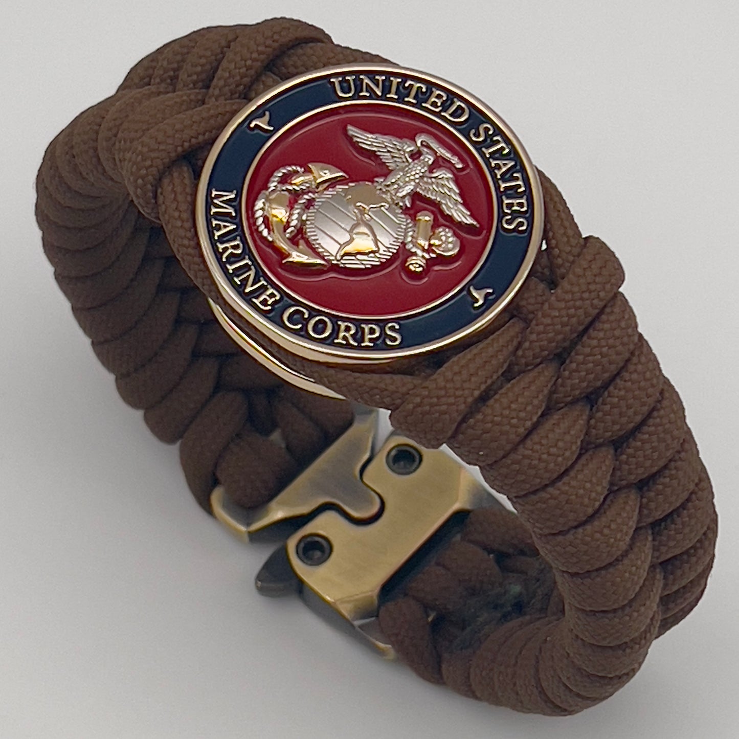 Thick and comfortable braided United States Marine Corps bracelet featuring a 24K gold and silver plated USMC officer Eagle Globe and Anchor medallion, a Cobra style tactical buckle and woven with Coyote brown 550 paracord.