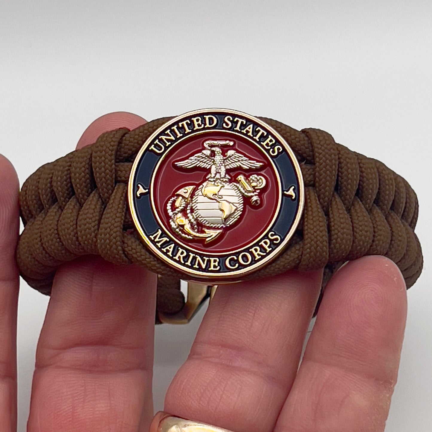 Thick and comfortable braided United States Marine Corps bracelet featuring a 24K gold and silver plated USMC officer Eagle Globe and Anchor medallion, a Cobra style tactical buckle and woven with Coyote brown 550 paracord.